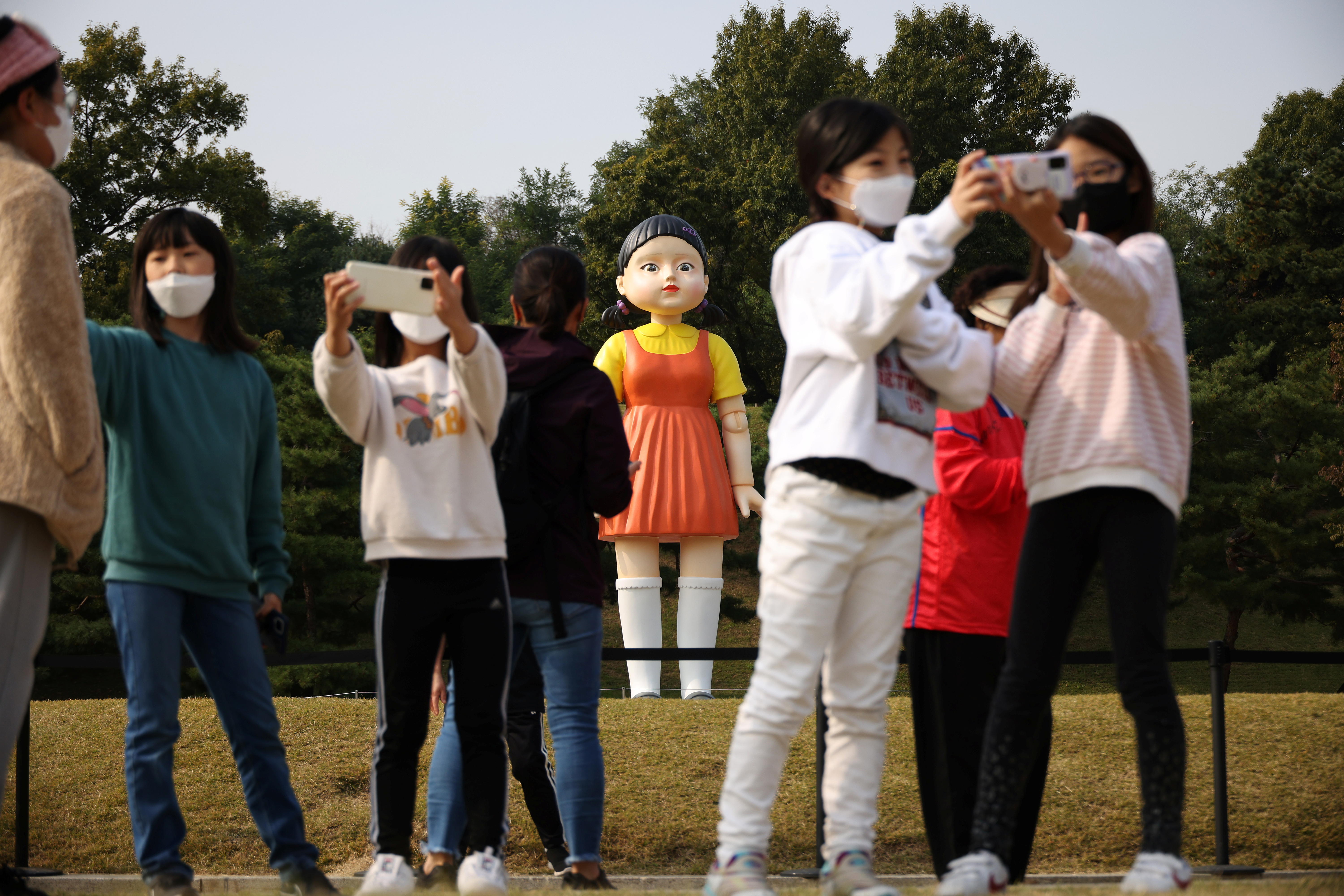 People take a selfie with a giant doll named 'Younghee' from Netflix series 'Squid Game' on display at a park in Seoul