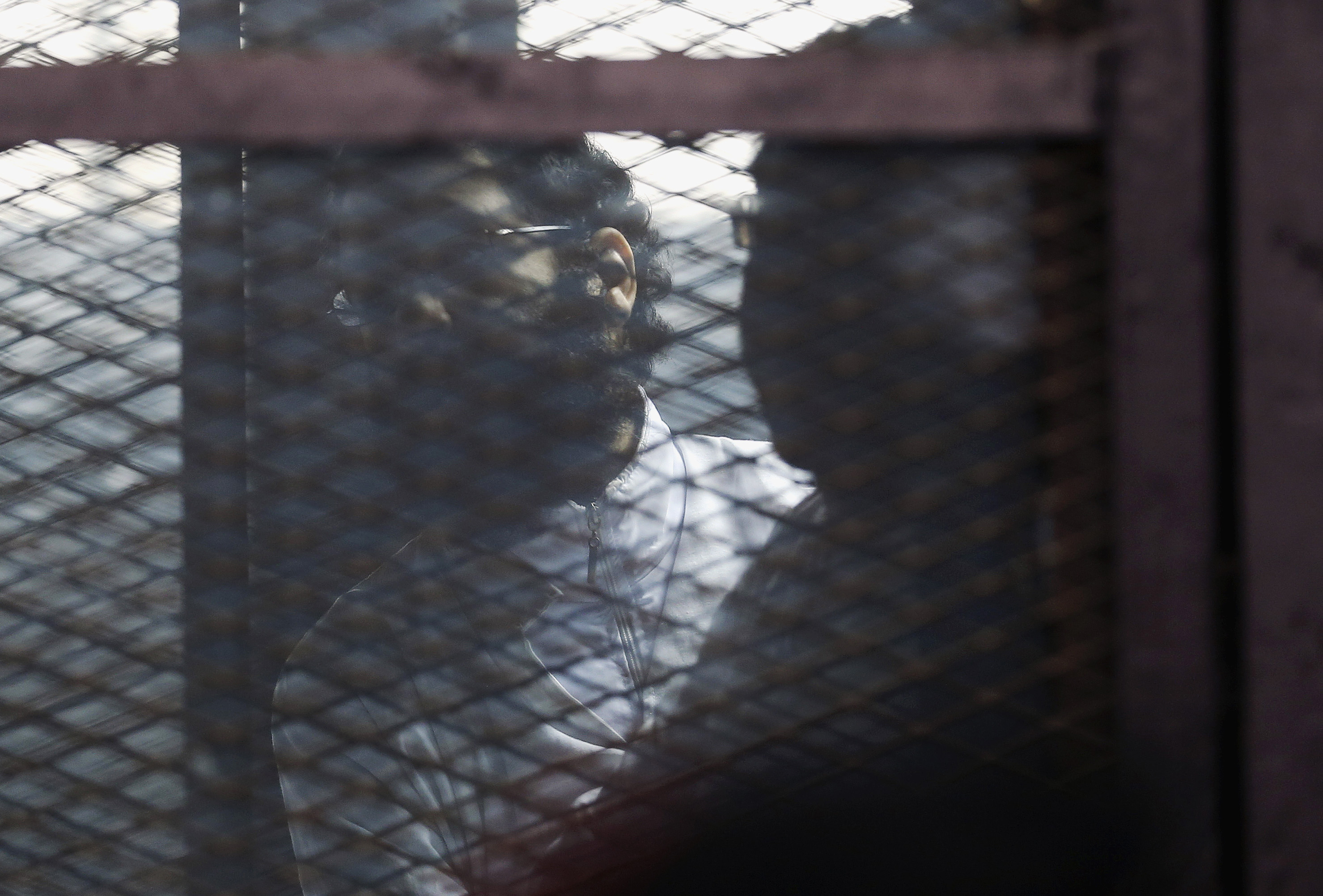Activist Alaa Abdel Fattah stands behind bars before his verdict is announced at a court in Cairo