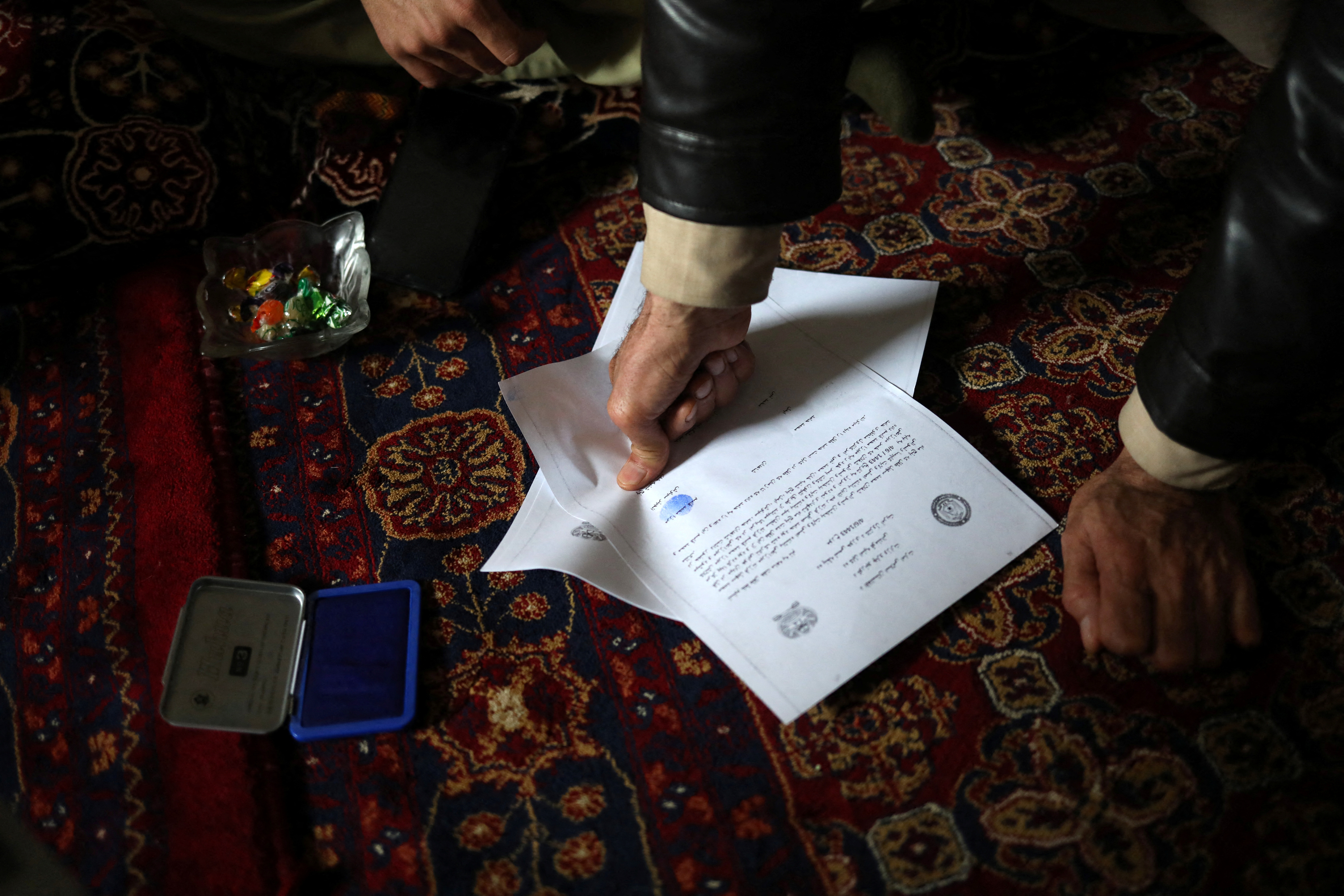 A relative of baby Sohail Ahmadi puts fingerprints on an agreement before the baby was handed over to his grandfather Mohammad Qasem Razawi in Kabul