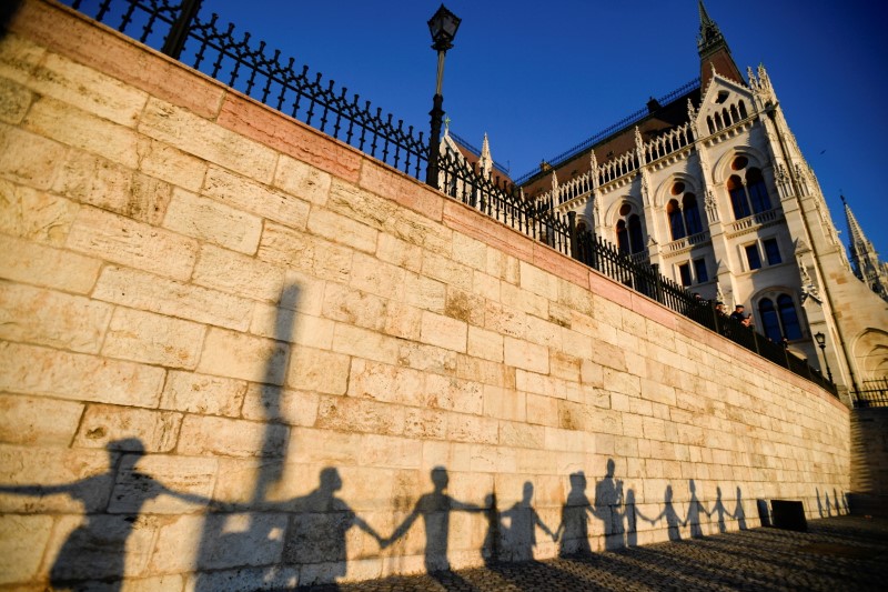 Silhouettes of demonstrators are seen as they march around the Hungarian parliament to protest against Hungarian Prime Minister Viktor Orban and the latest anti-LGBTQ law in Budapest, Hungary, June 14, 2021. REUTERS/Marton Monus/File Photo