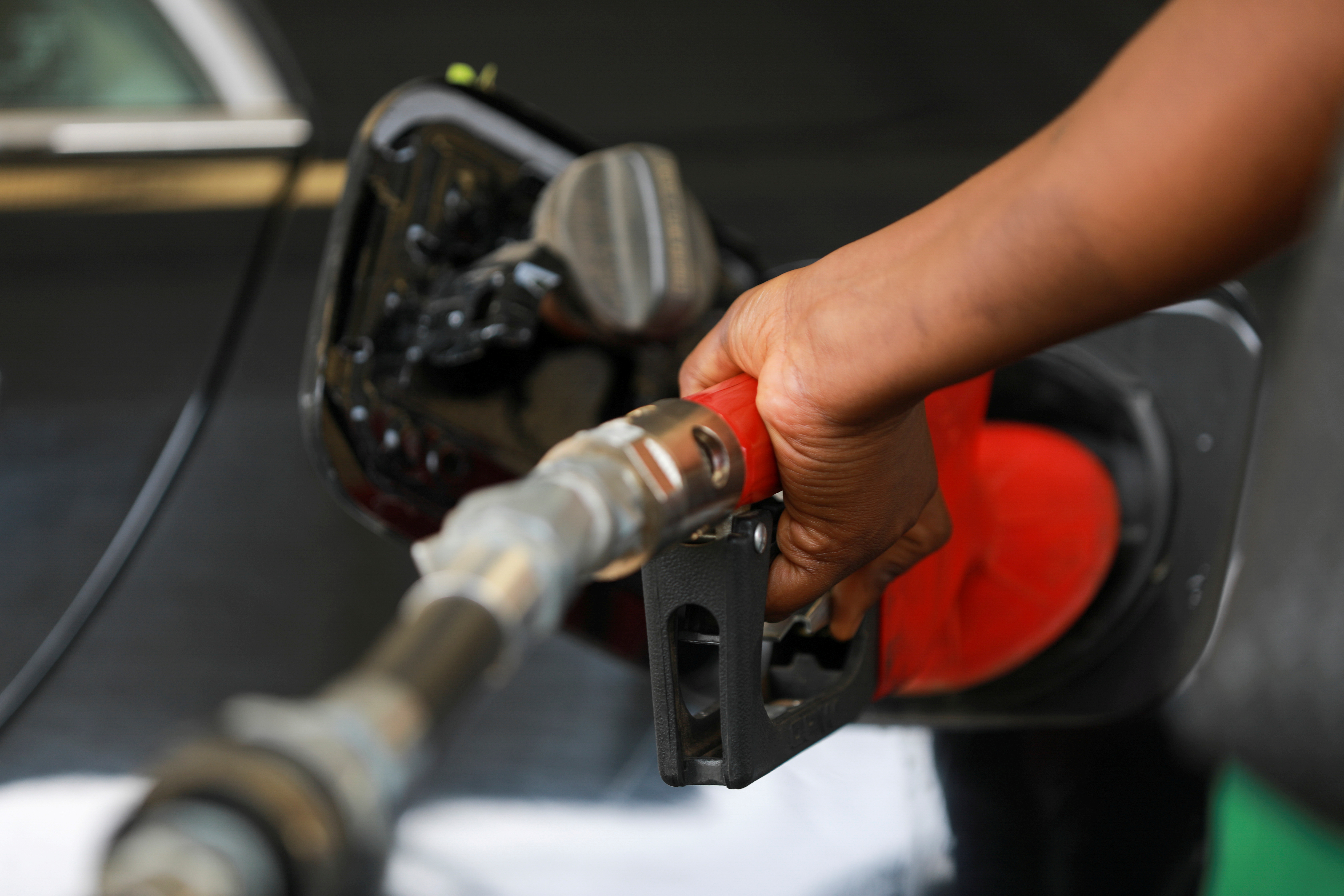 A gas station attendant pumps fuel into a customer's car at the NNPC Mega petrol station in Abuja