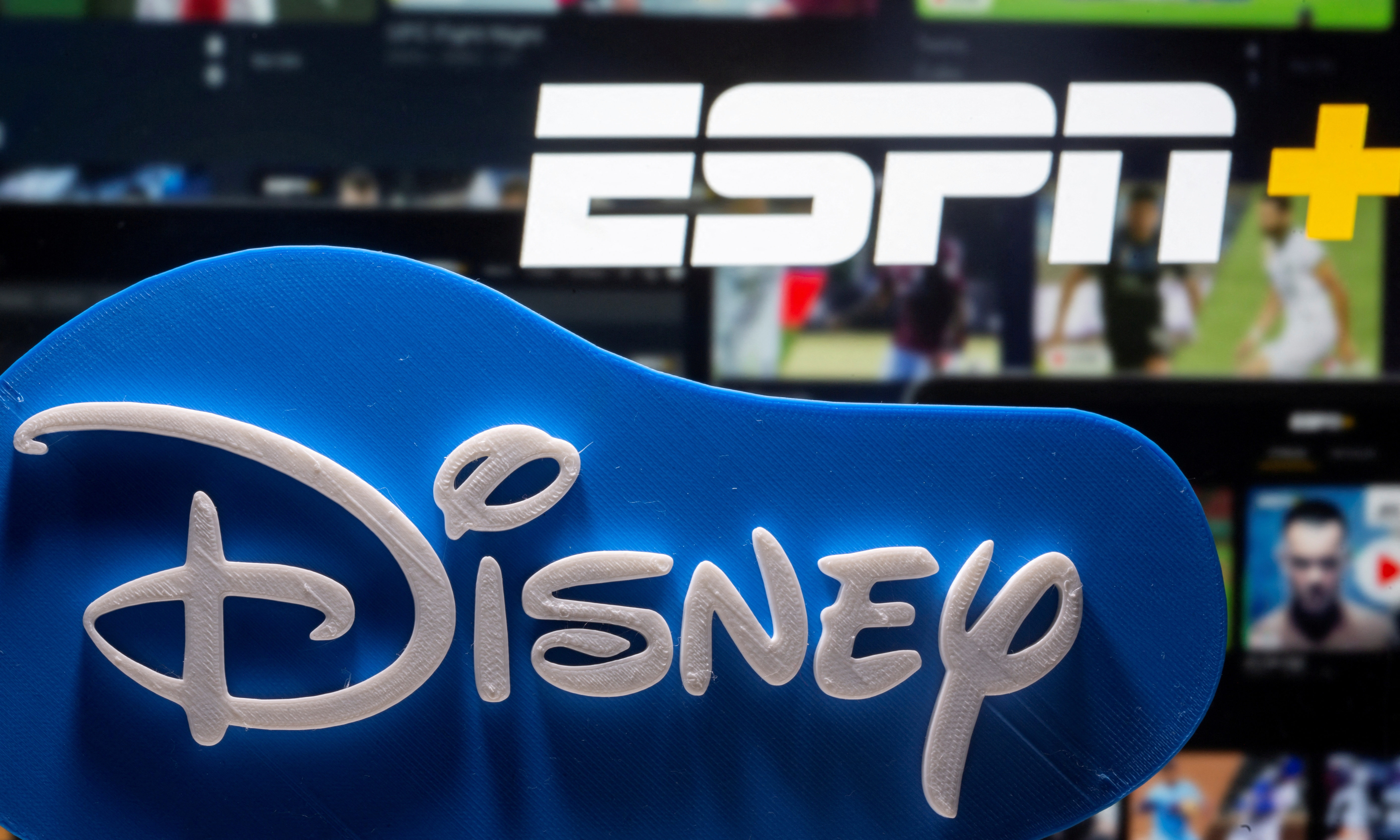 Photo illustration of a 3D-printed Disney logo seen in front of the ESPN+ logo