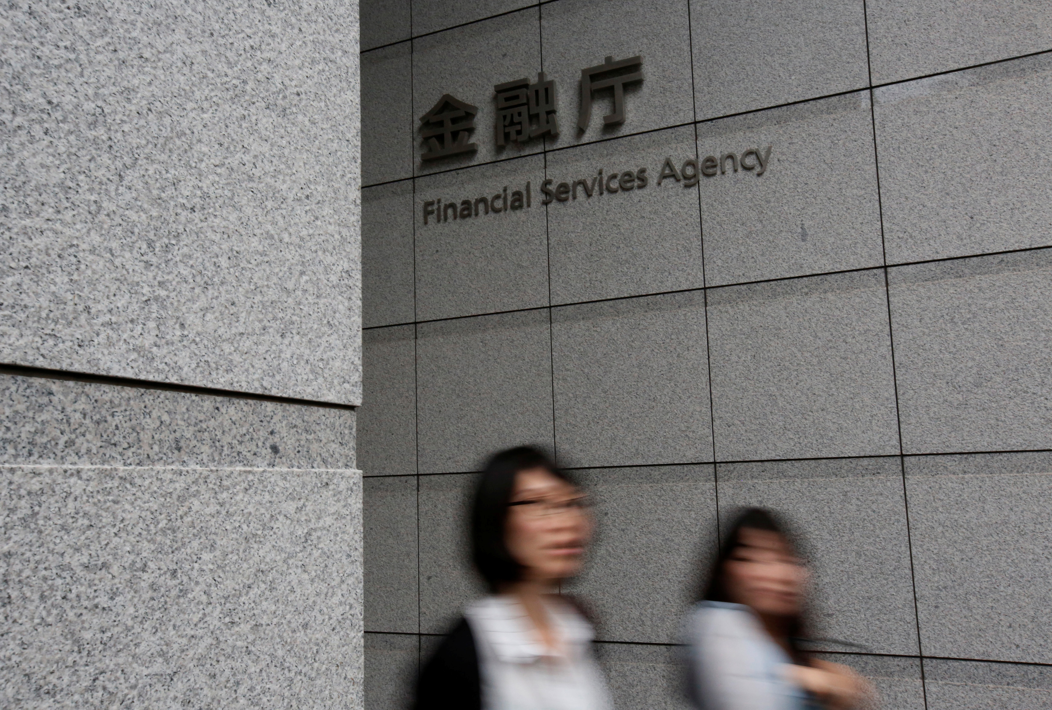 Women walk under a sign of Japan's Financial Services Agency in Tokyo, Japan