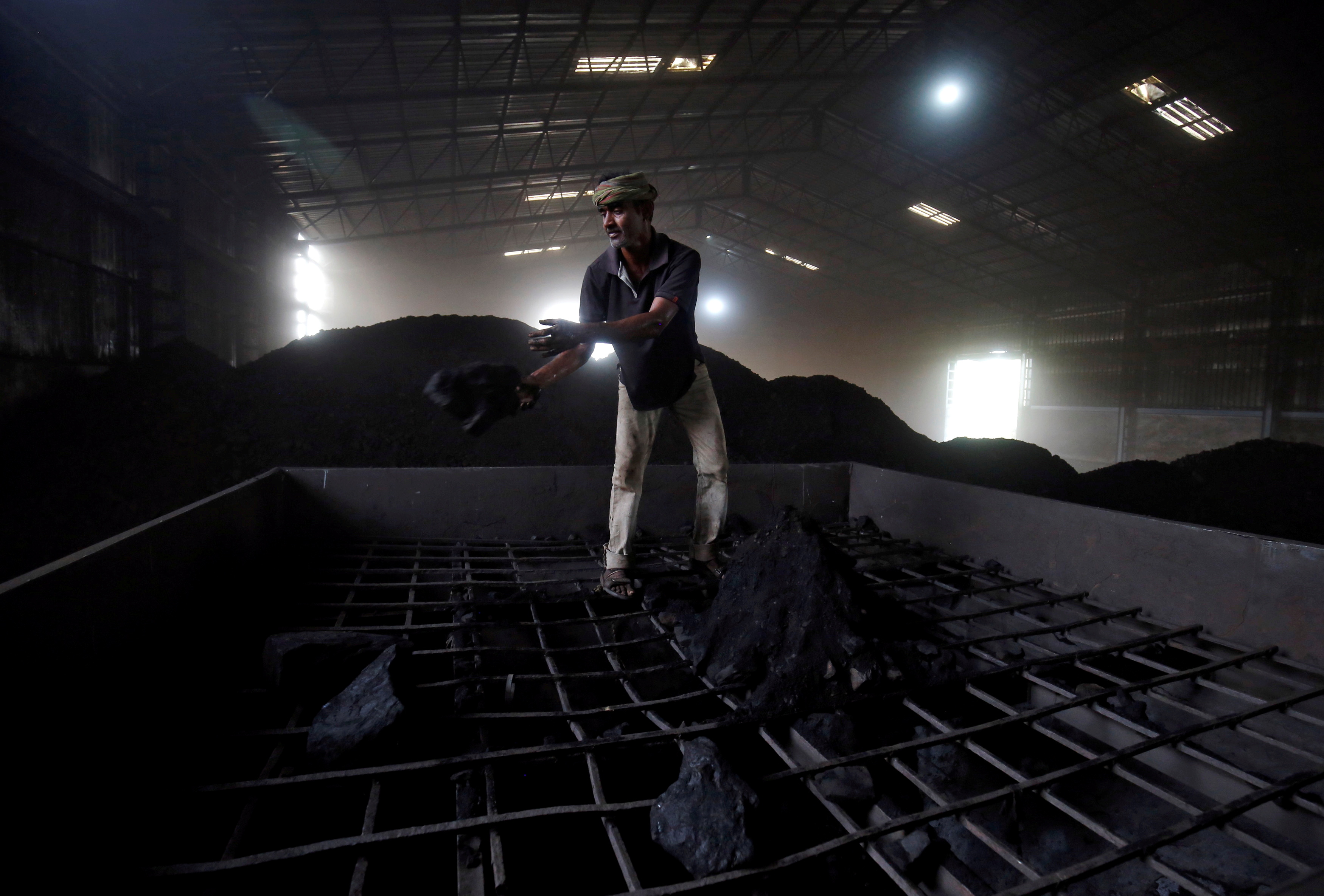 A worker shovels coal in a supply truck at a yard on the outskirts of Ahmedabad