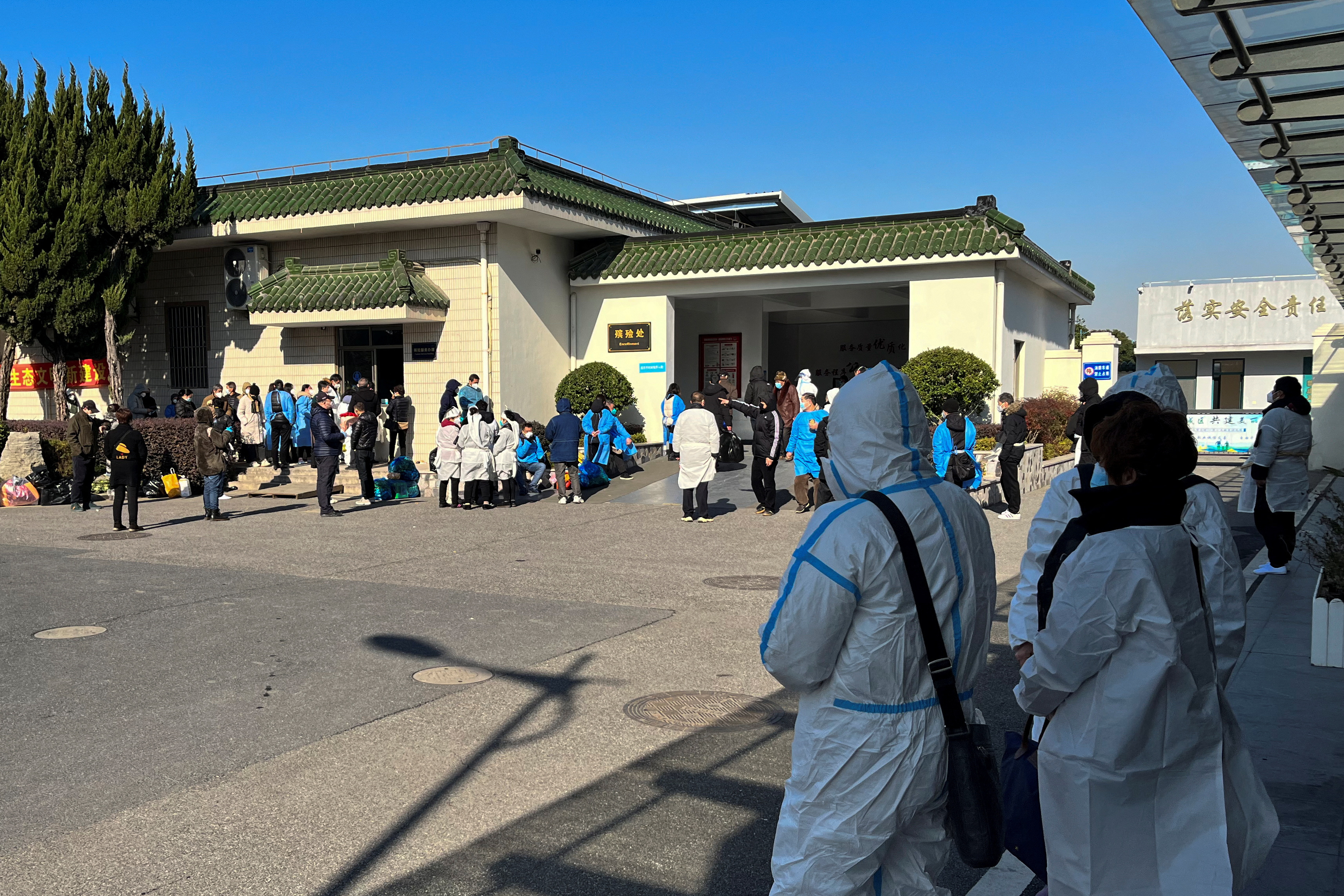 People some wearing personal protective equipment (PPE) stand outside a funeral home, as coronavirus disease (COVID-19) outbreak continues, in Shanghai