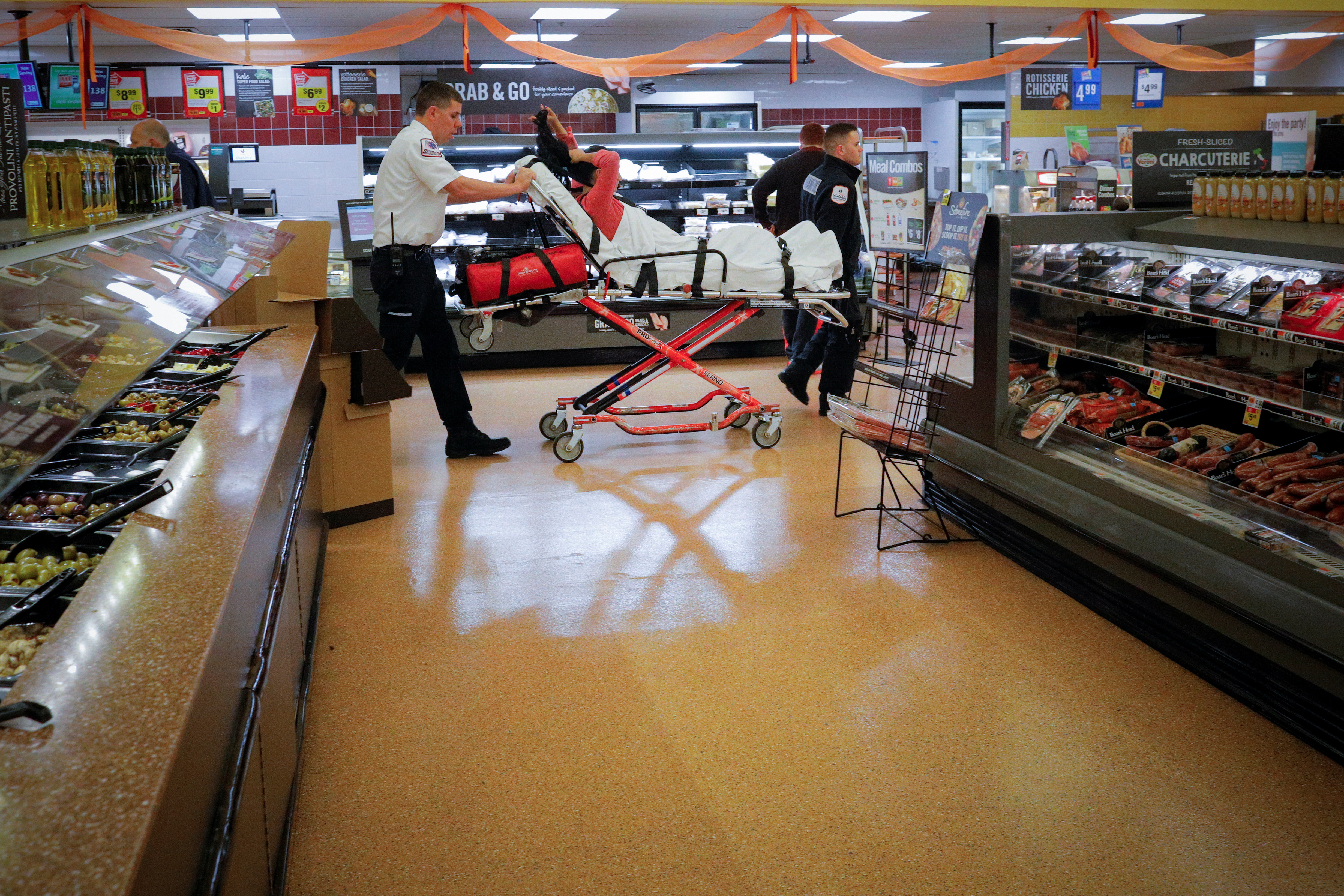 Cataldo Ambulance medics Ricky Cormio (L) and Luke Magnant take a 40-year-old woman out of a grocery store where she was found unresponsive in the store's bathroom after overdosing on opioids in the Boston suburb of Malden