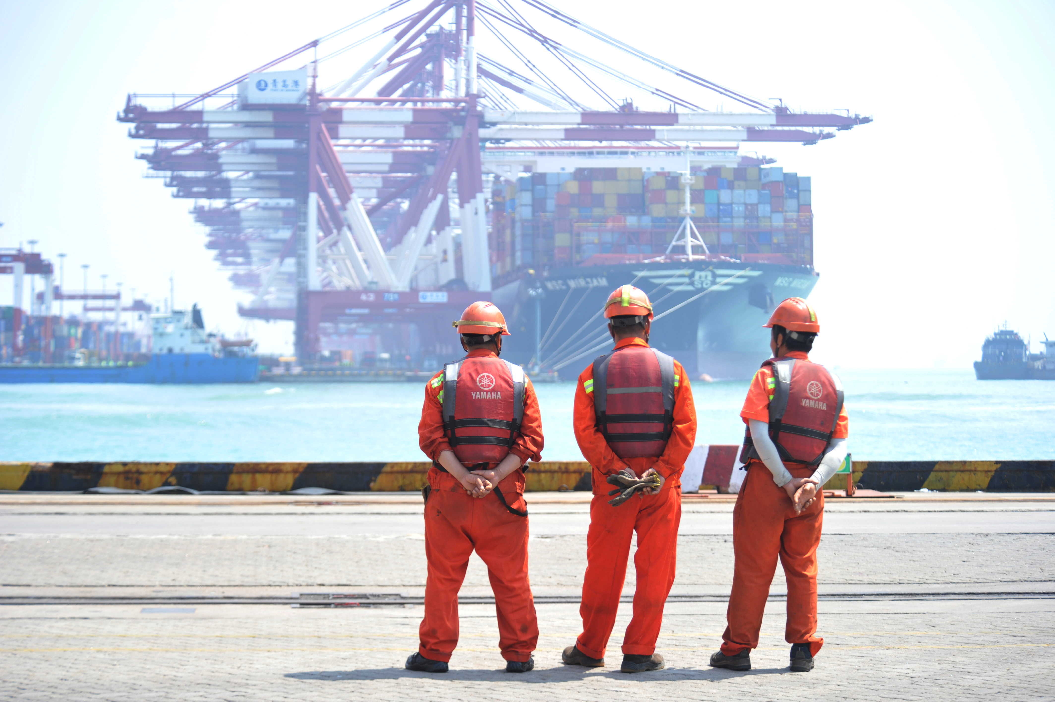 Workers stand at the port of Qingdao, Shandong