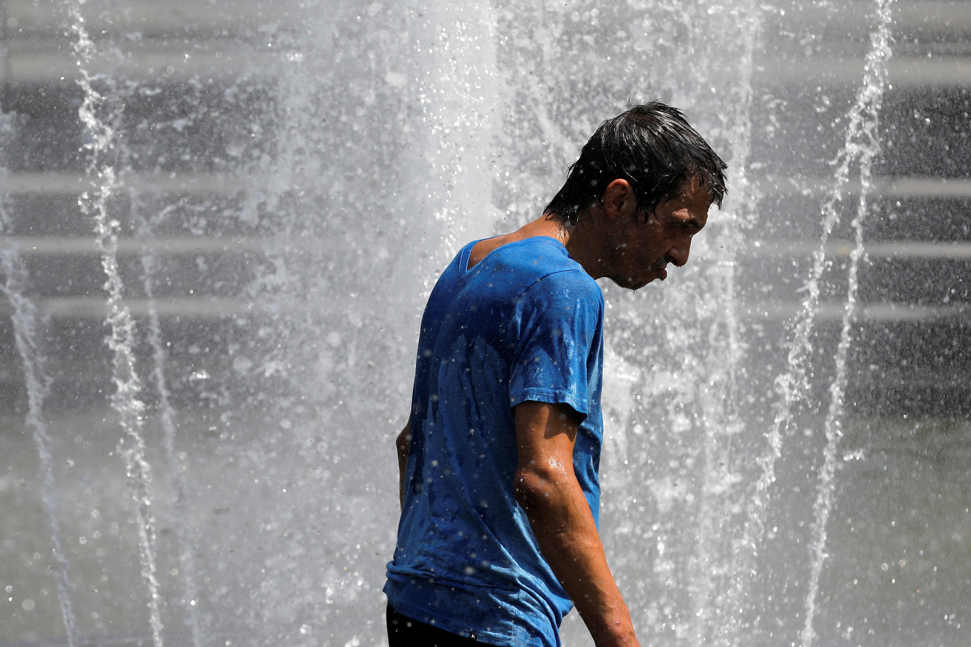 A man walks in the fountain in Washington Square Park as a heat wave hit the region in Manhattan, New York City, U.S., August 12, 2021. REUTERS/Andrew Kelly
