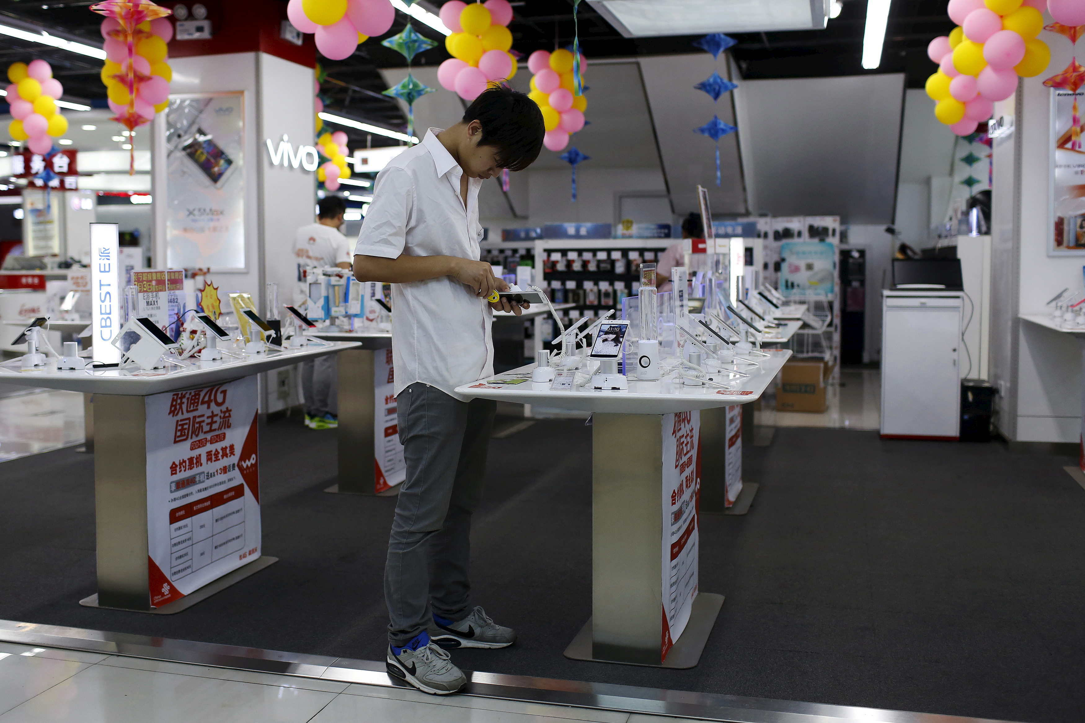 A customer look at a mobile phone on display at an electronics market in Shanghai