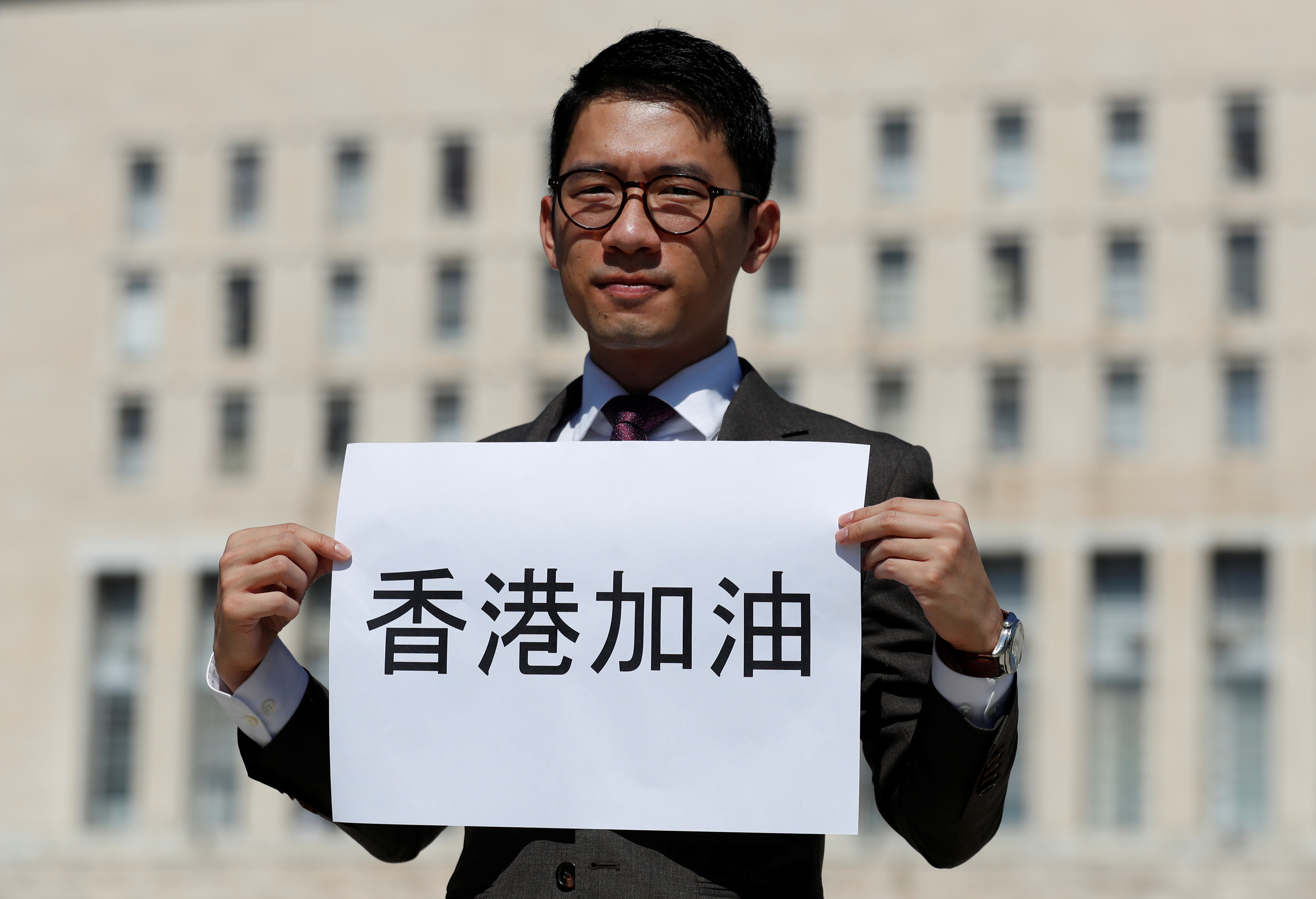 Exiled Hong Kong pro-democracy activist Nathan Law holds a placard outside the Italian Foreign Ministry in Rome