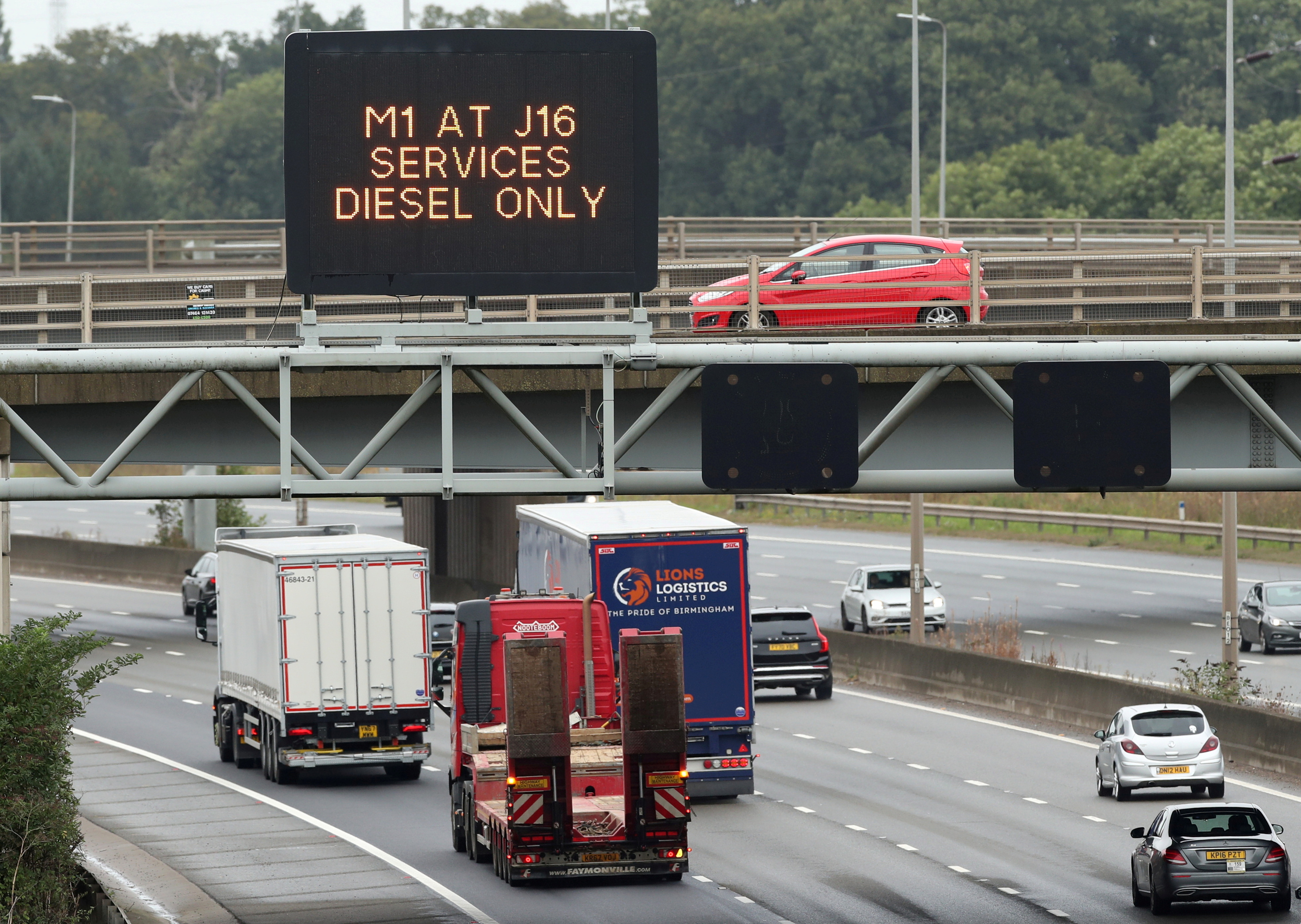 Lorries drive past a fuel warning sign on the M1 motorway amid a fuel shortage, in Luton, Britain