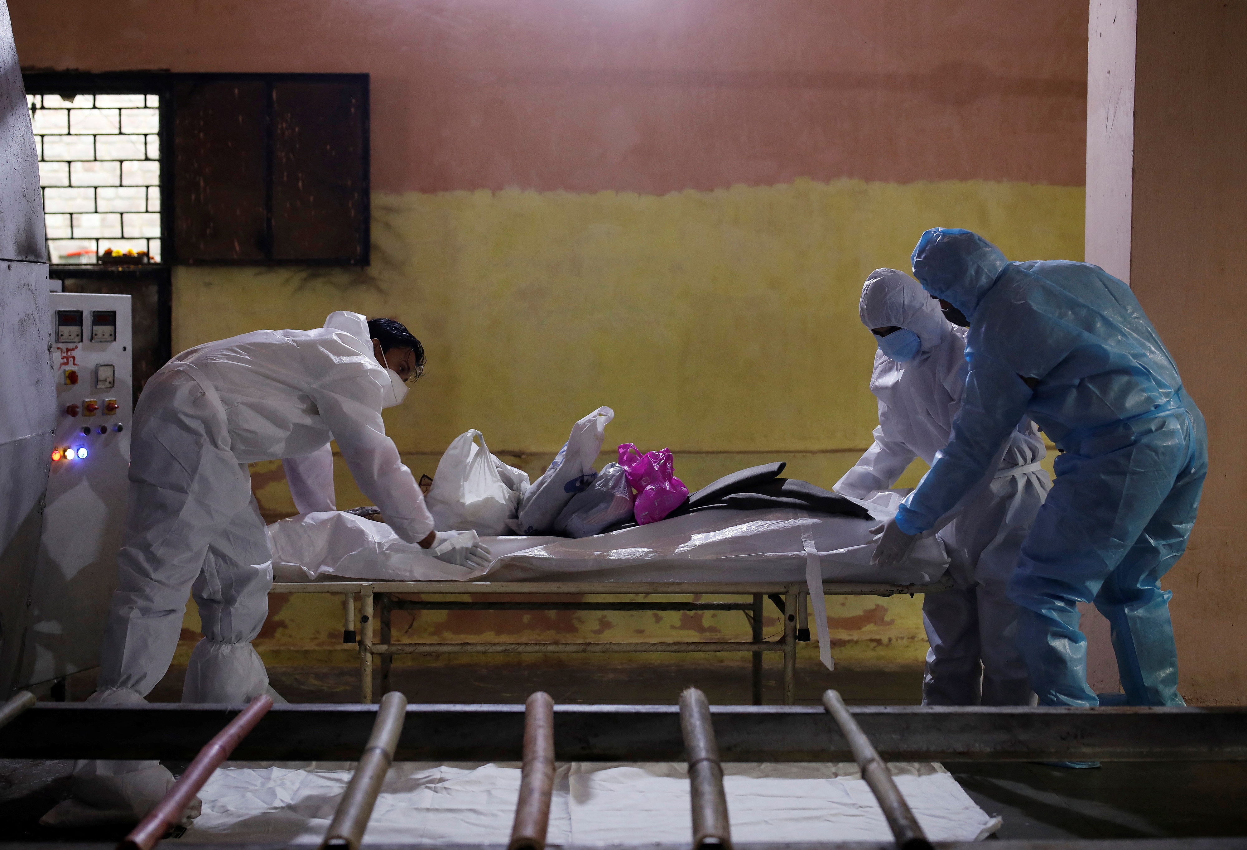Health workers wearing personal protective equipment (PPE) carry the body of Ramdhan who died from the coronavirus disease (COVID-19) at a crematorium in New Delhi