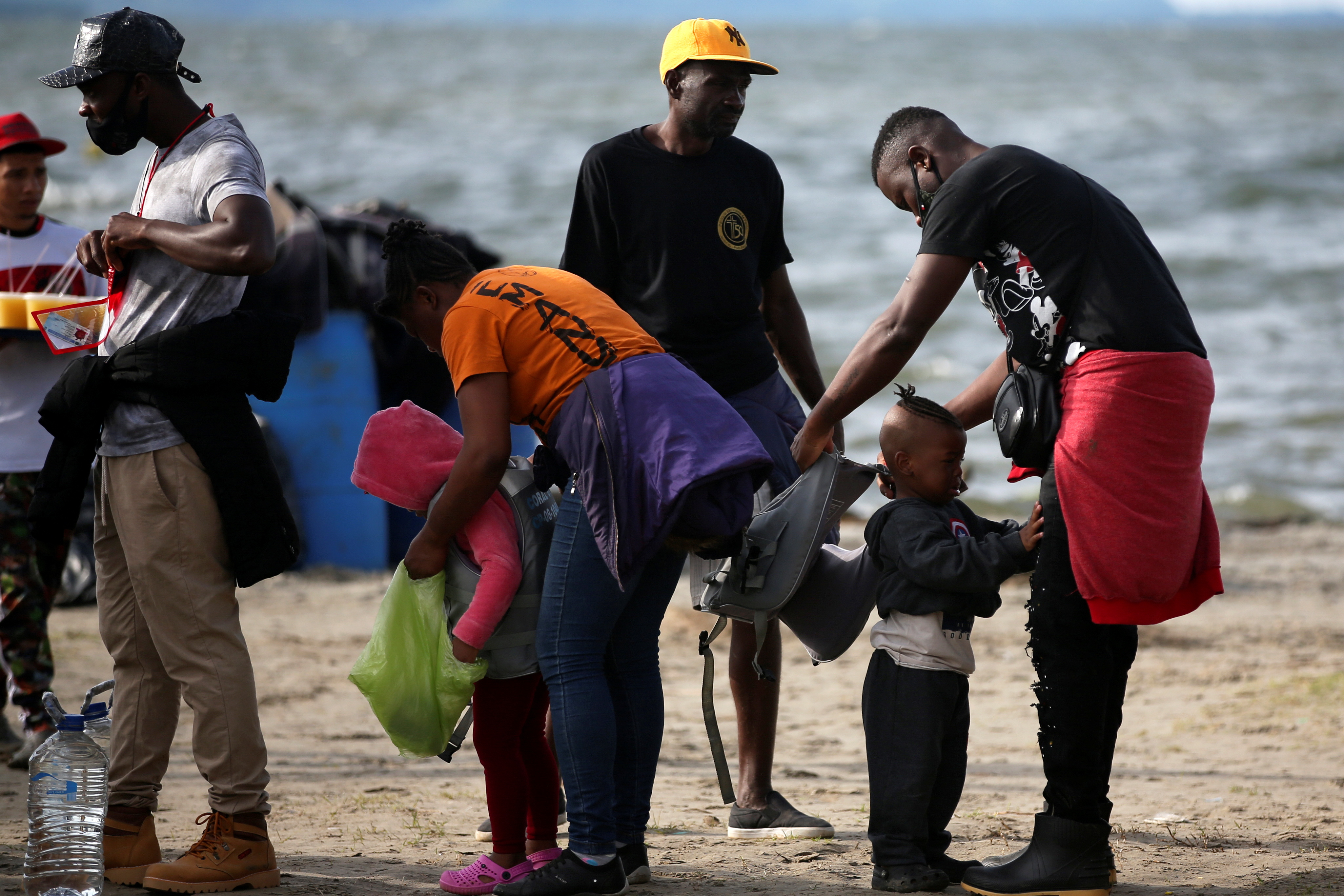 A migrant family puts life jackets on their children to board a boat that will take them to Acandi to cross to Panama in order to continue their journey towards the U.S., in Necocli, Colombia, September 23, 2021.   REUTERS/Luisa Gonzalez