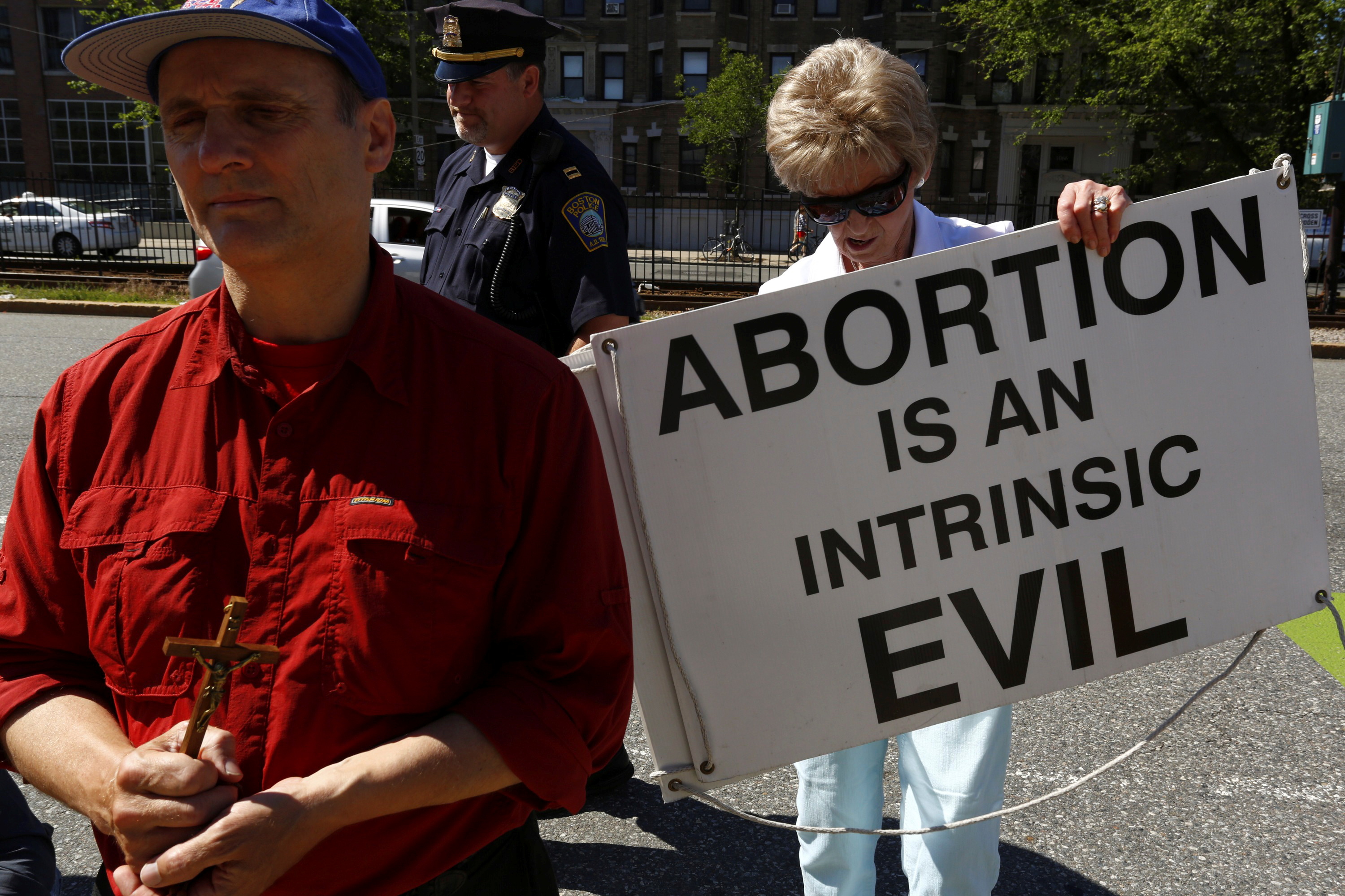 An abortion protester moves her sign out of the street in front of a Planned Parenthood clinic in Boston, Massachusetts