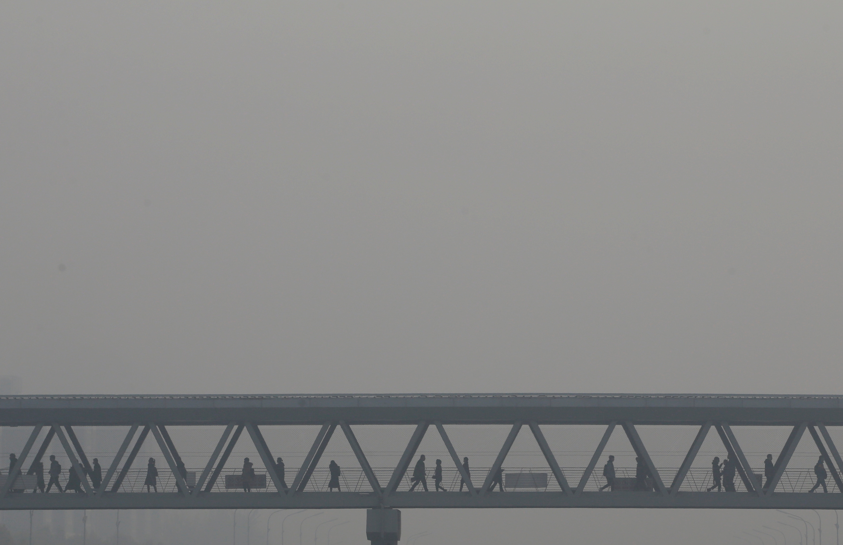 People walk on a pedestrian bridge as heavy smog blankets China's capital Beijing