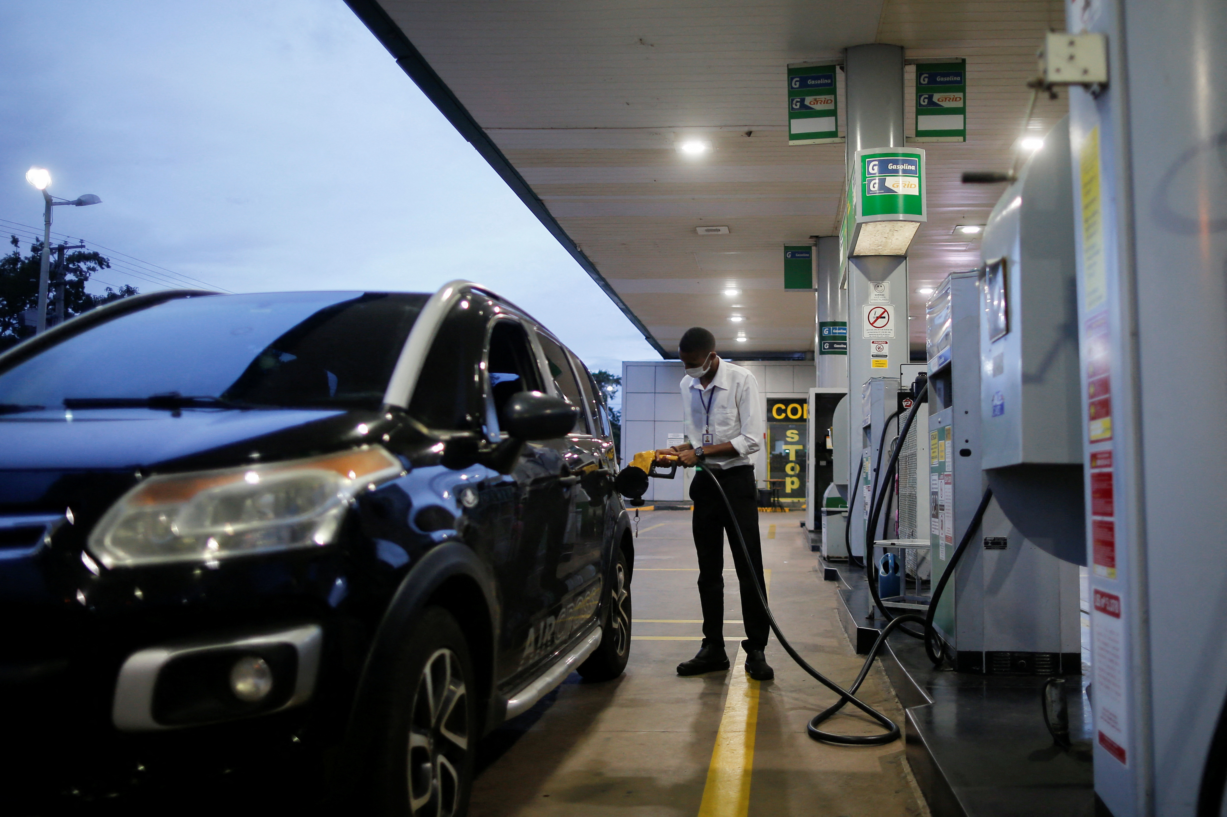 A worker uses a petrol pump at a Brazilian oil company Petrobras gas station in Brasilia