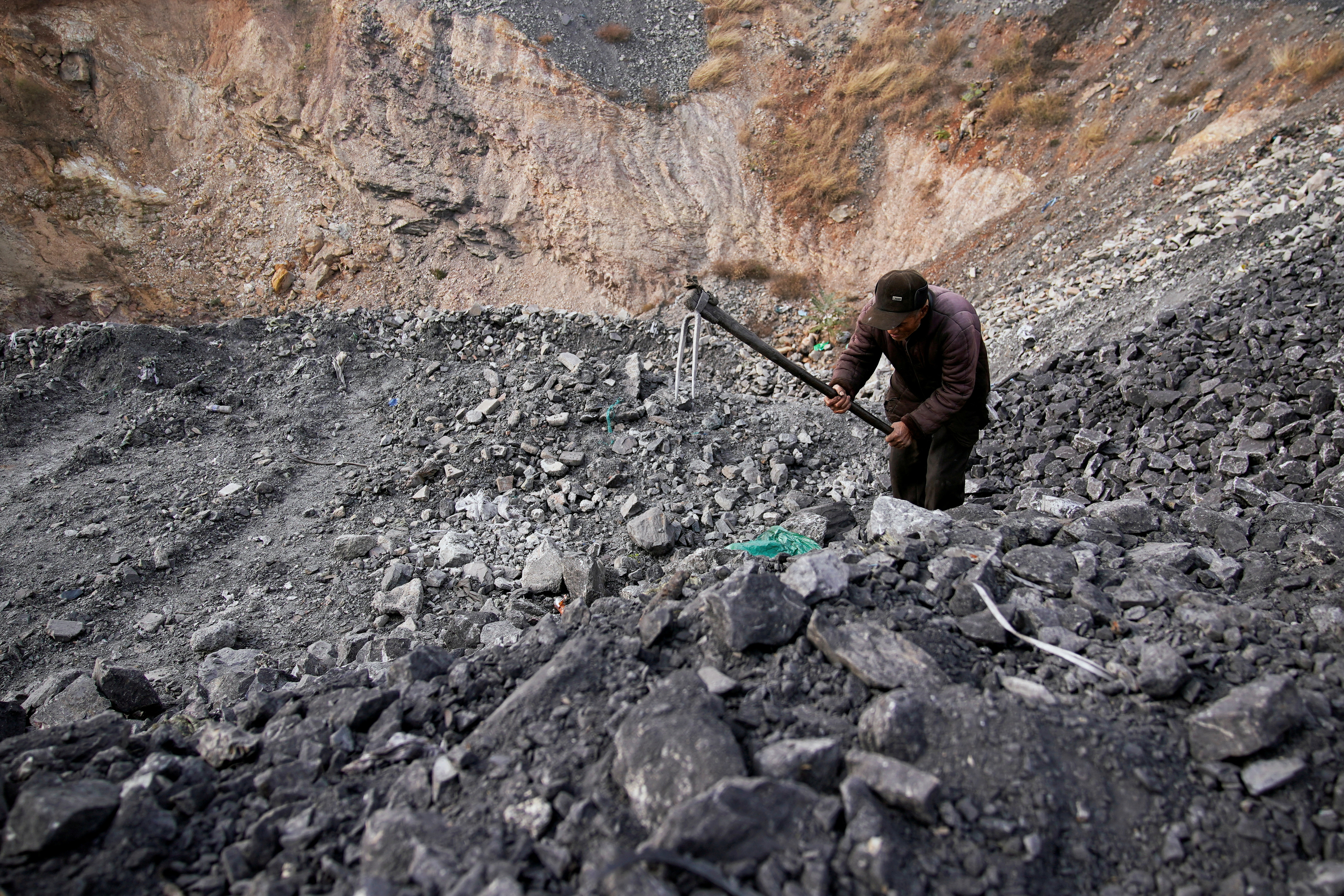 A man sifts through dunes of low-grade coal near a coal mine in China