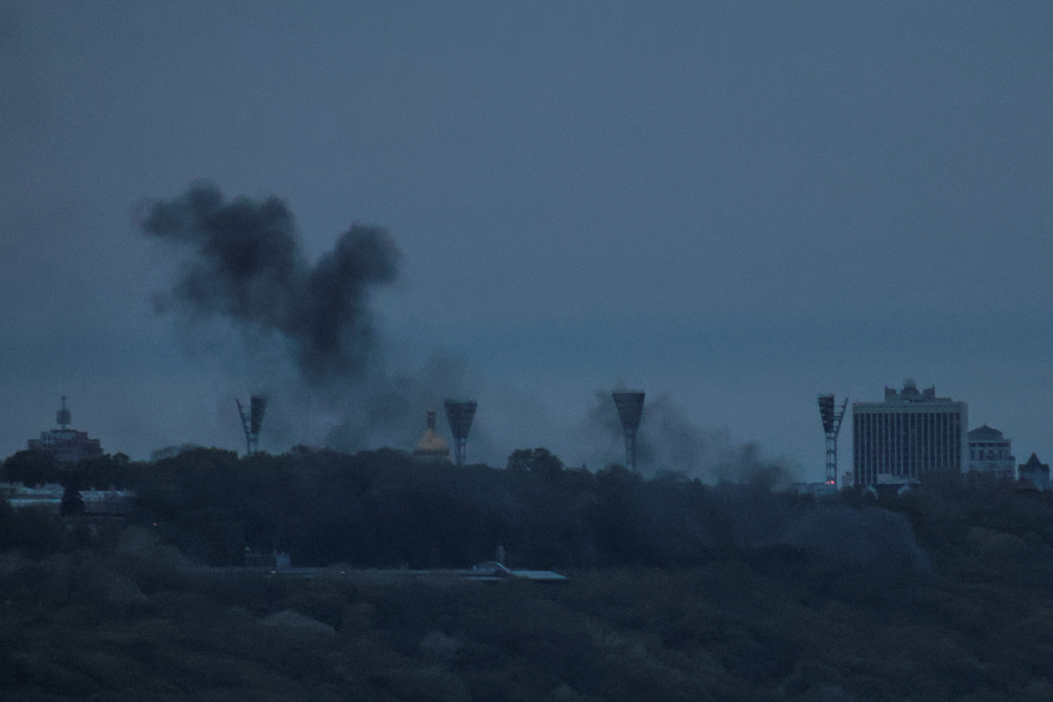 Smoke rises over the city after the wreckage of a downed Russian drone lands on a building in Kiev