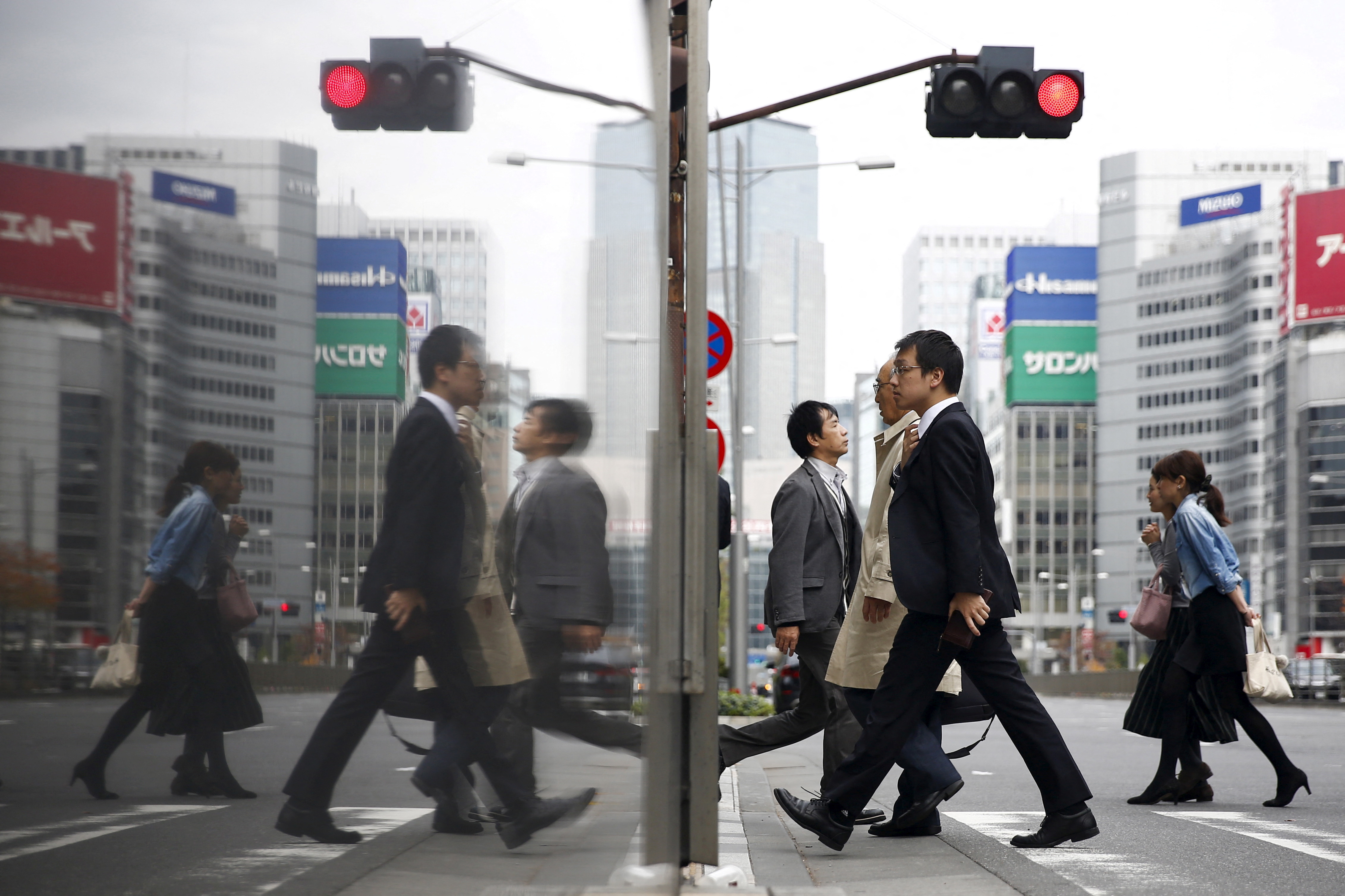 People cross a street in a business district in central Tokyo