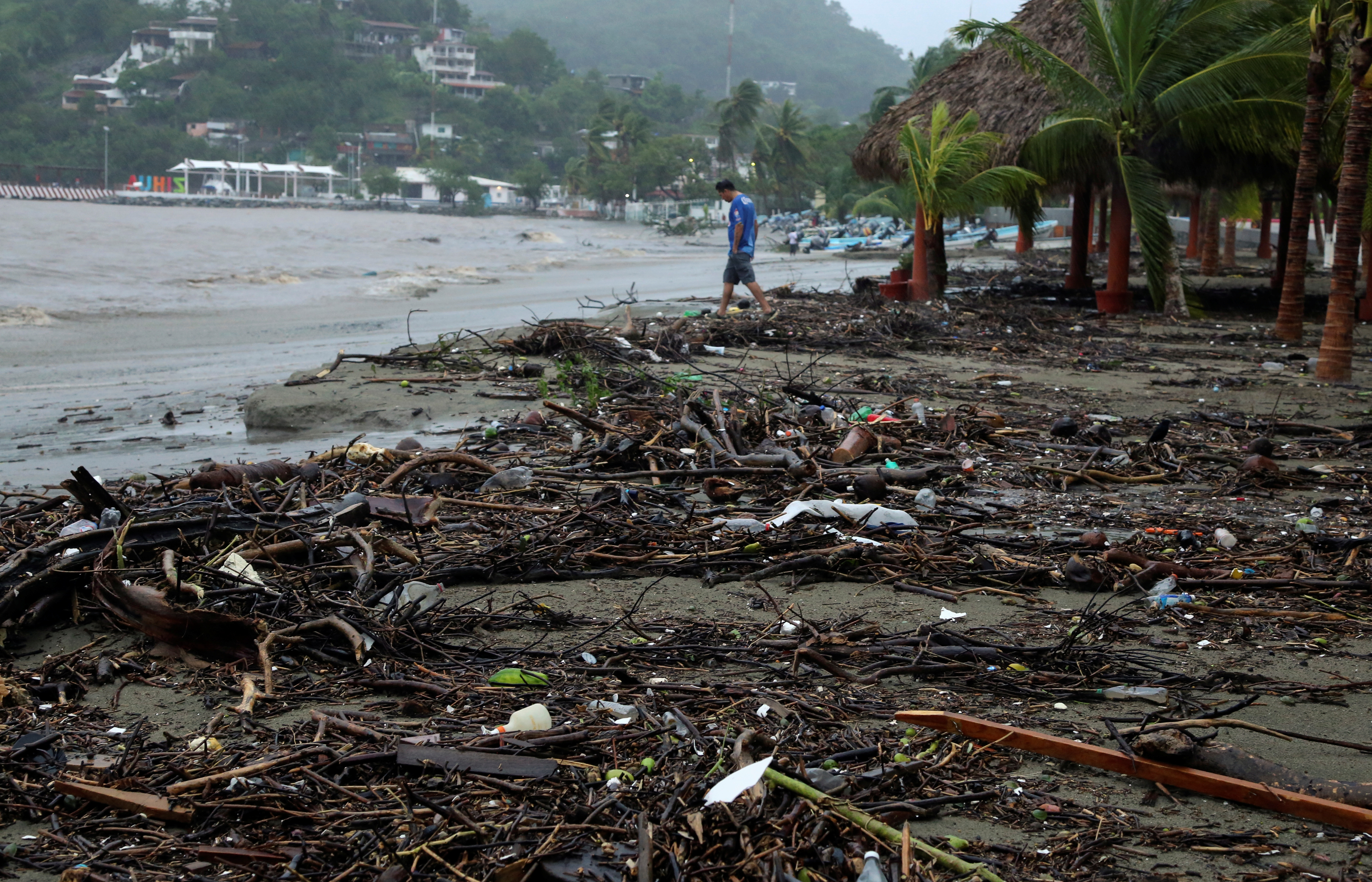A man walks along the beach covered with tree branches and derbis after Hurricane Rick hit in Zihuatanejo, in Guerrero state, Mexico October 25, 2021. REUTERS/Javier Verdin