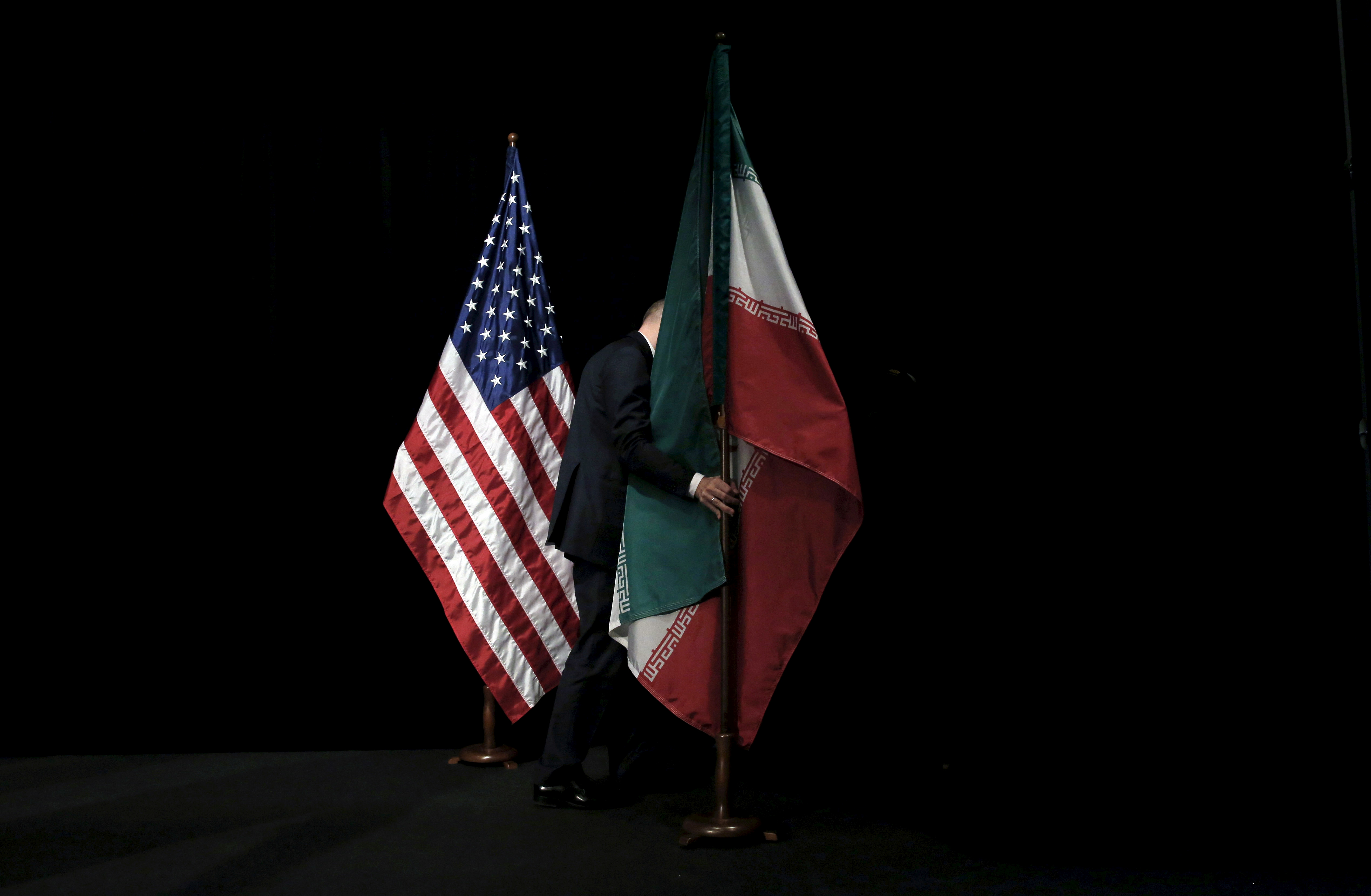 A staff member removes the Iranian flag from the stage after a group picture with foreign ministers and representatives of United States, Iran, China, Russia, Britain, Germany, France and the European Union during the Iran nuclear talks at the Vienna Inte