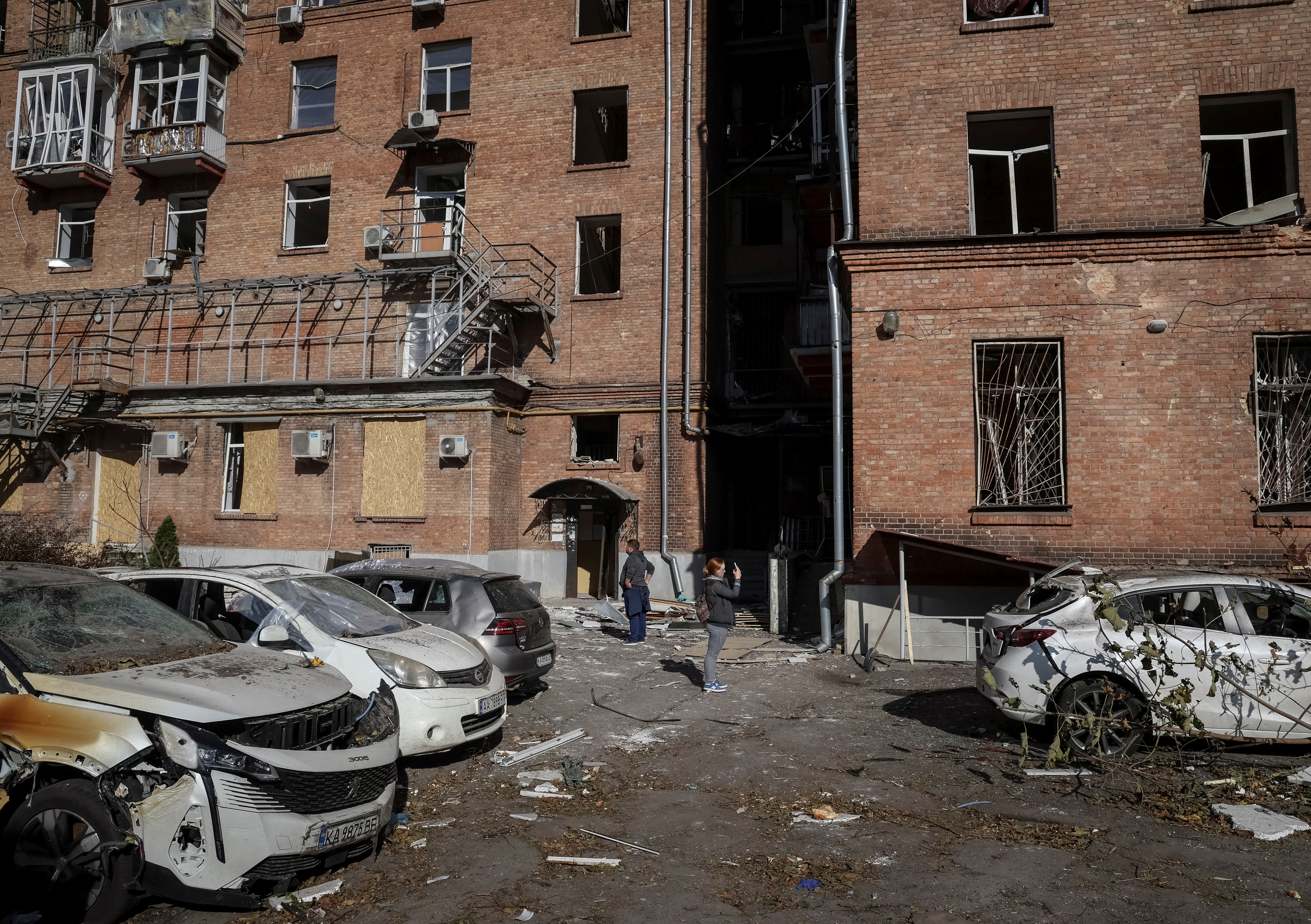 Local residents stand near their apartment building, damaged by the previous day's Russian military strike, as Russia's attack on Ukraine continues, in central Kyiv
