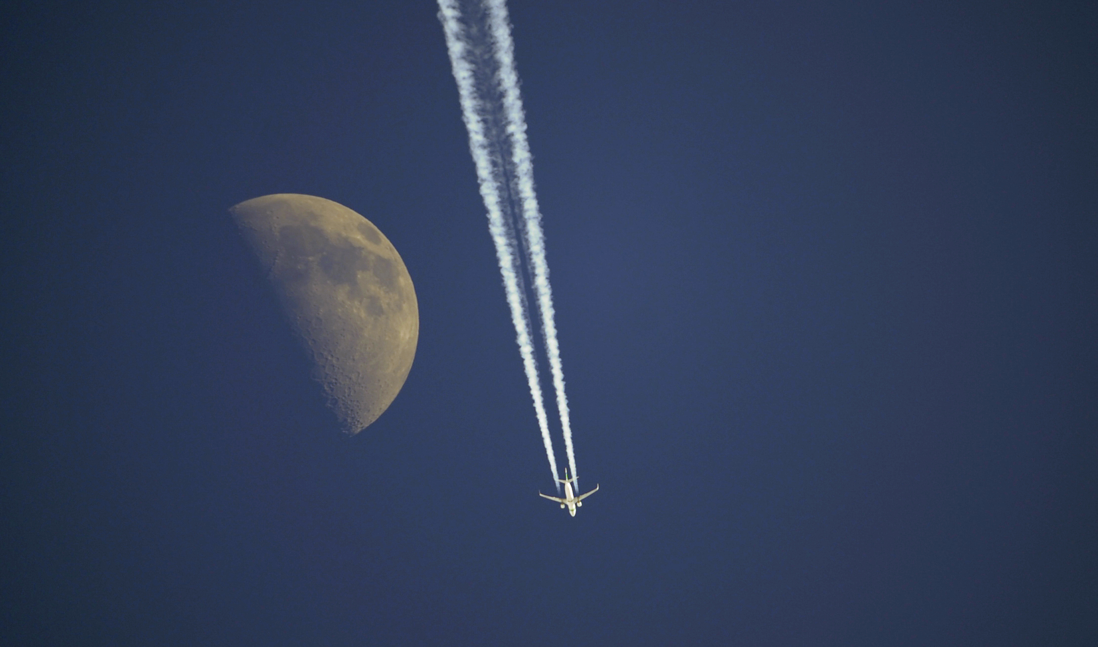 An aircraft flies past the moon over Anterselva