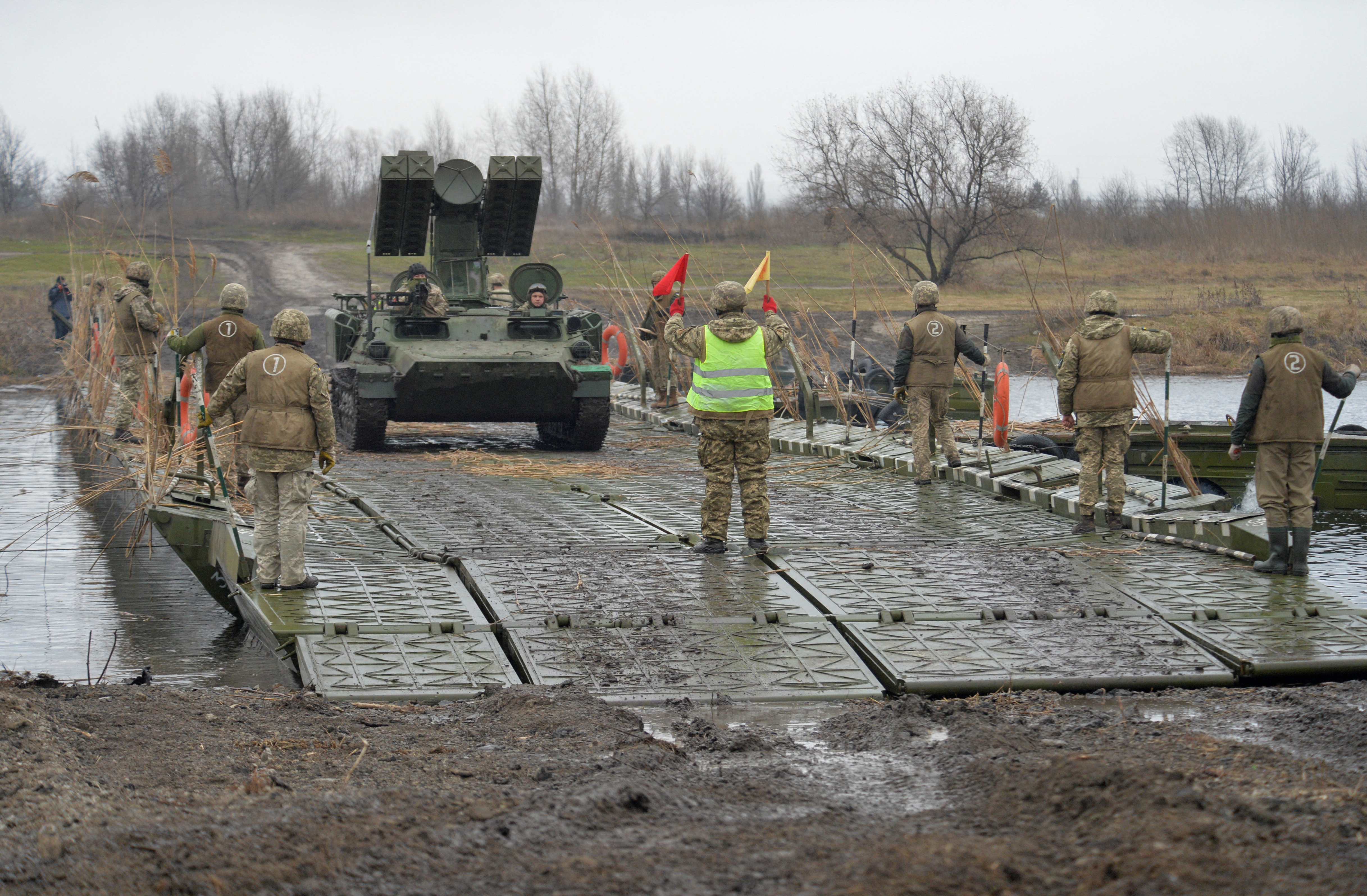 Service members of the Ukrainian armed forces drive a self-propelled rocket launcher along a pontoon bridge while crossing the Aidar River during military drills near Novoaidar in the Luhansk region, Ukraine, December 14, 2021. REUTERS/Oleksandr Klymenko