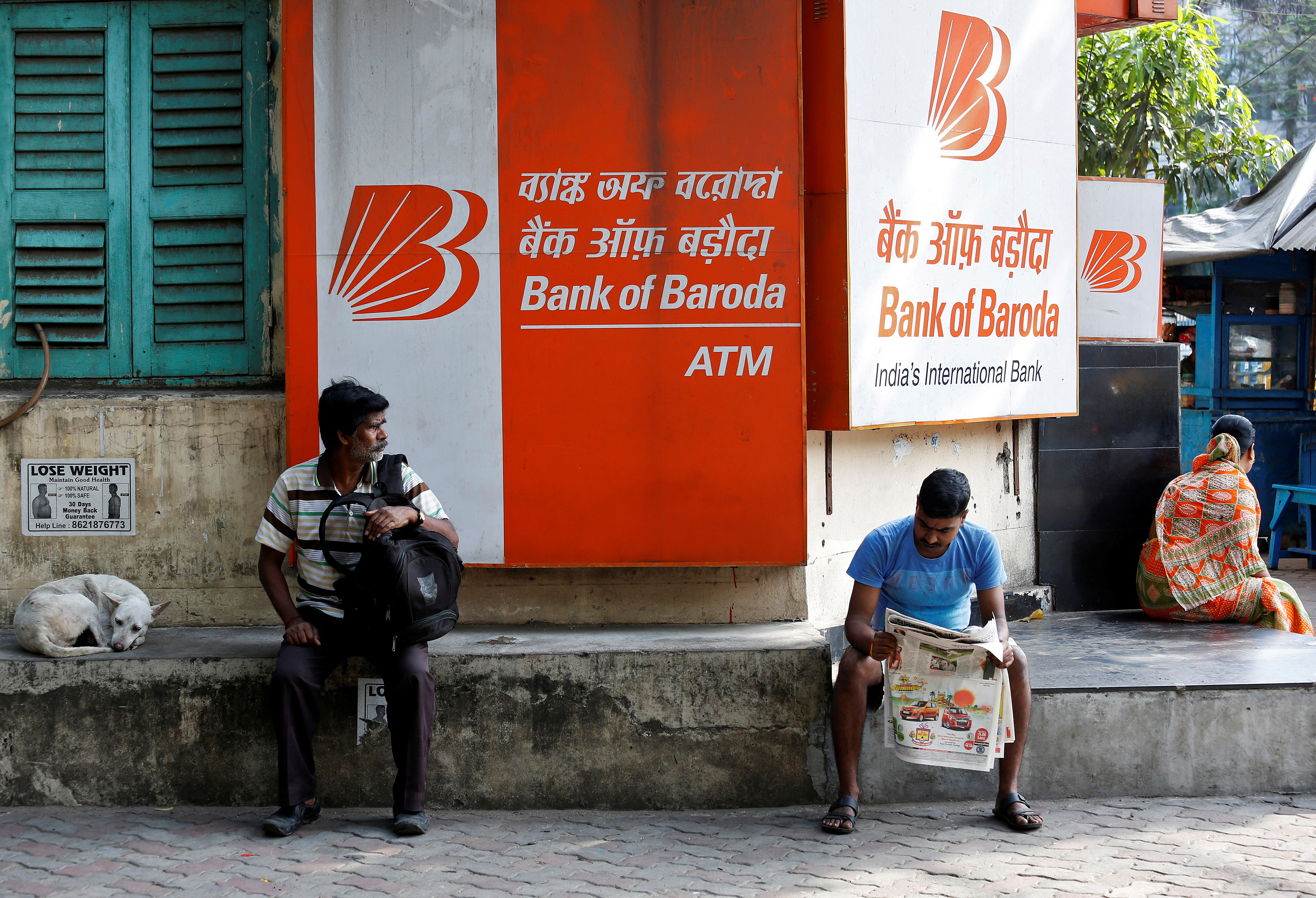 People sit outside Bank of Baroda's branch in Kolkata