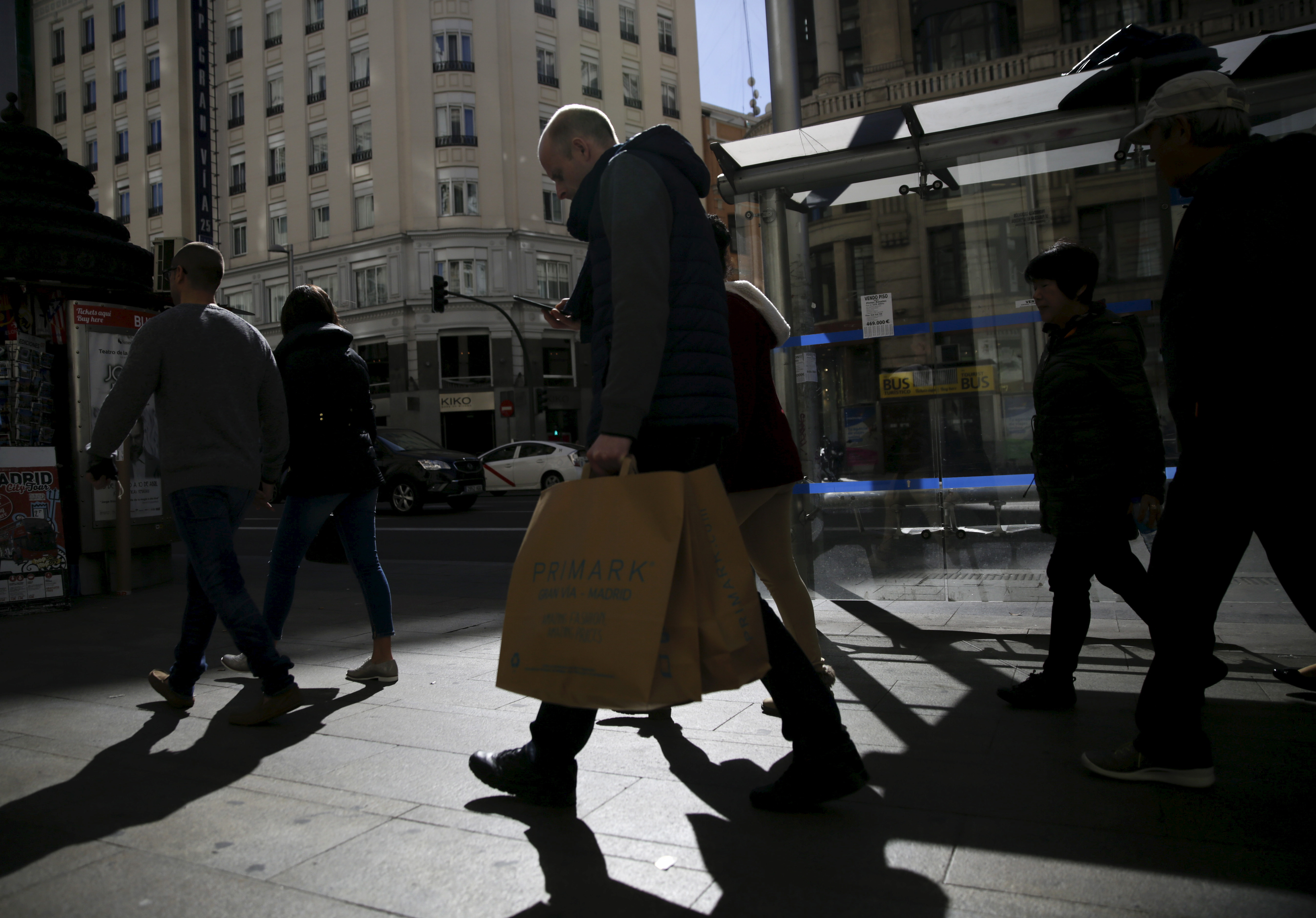 People carry shopping bags at a shopping district in Madrid, Spain