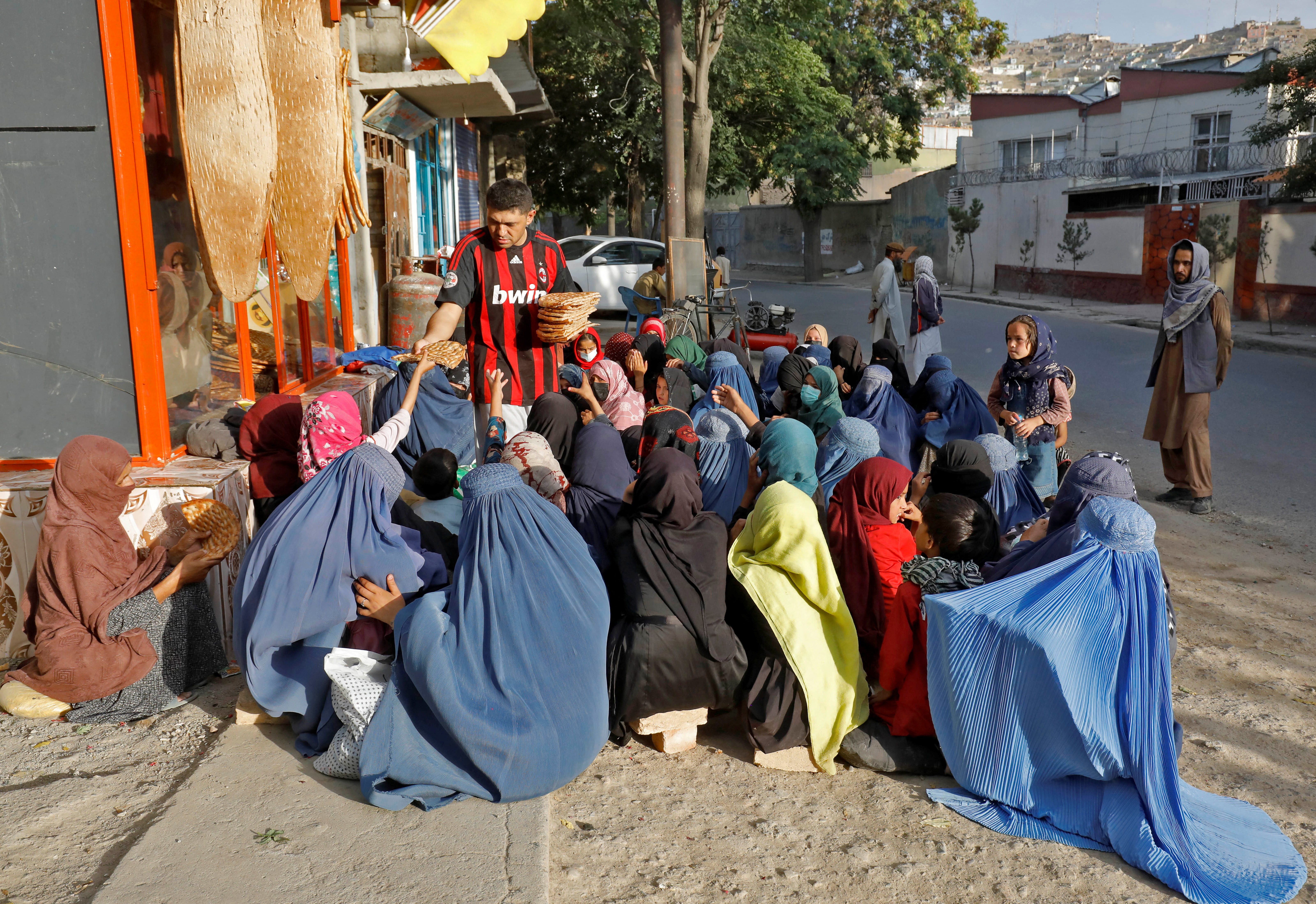 An Afghan girl receives a loaf of bread in front of a bakery among the crowd in Kabul