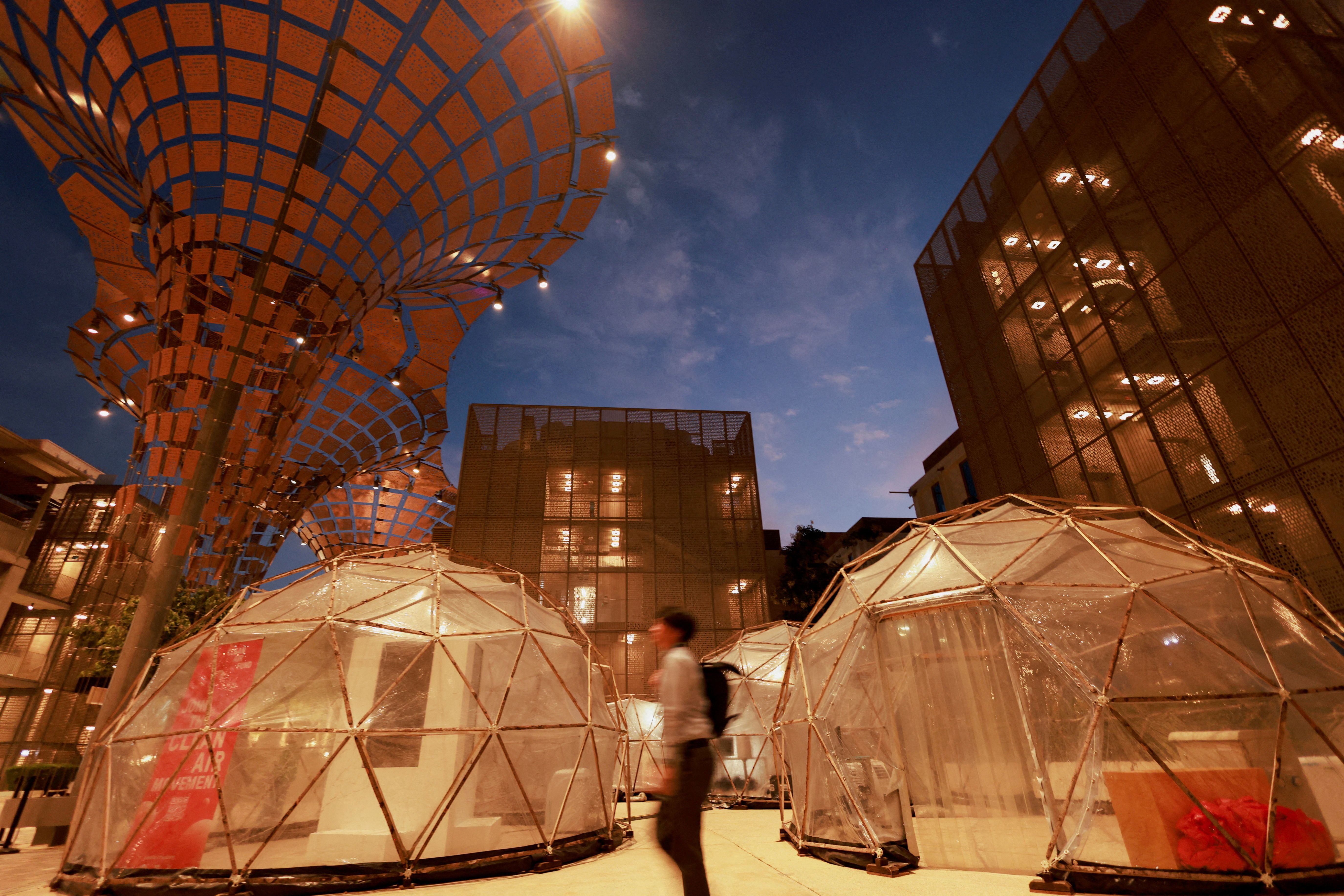 A man walks past a pollution pod designed to mimic the air quality in New Delhi, during the United Nations Climate Change Conference (COP28), in Dubai