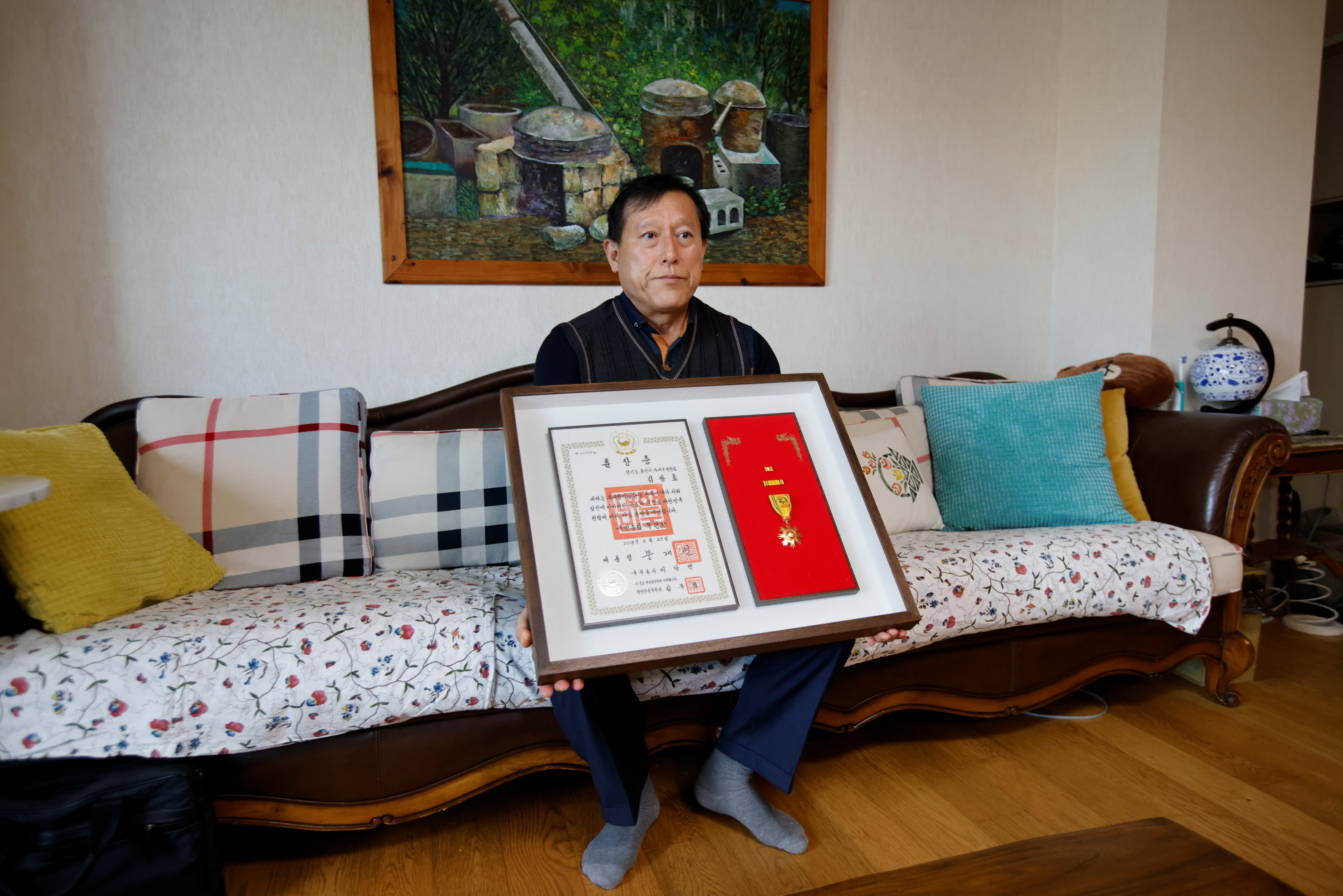 Kim Gwang-ho, a former Hyundai Motor engineer, poses with a presidential certificate recognizing his anti-corruption work at his home in Seoul