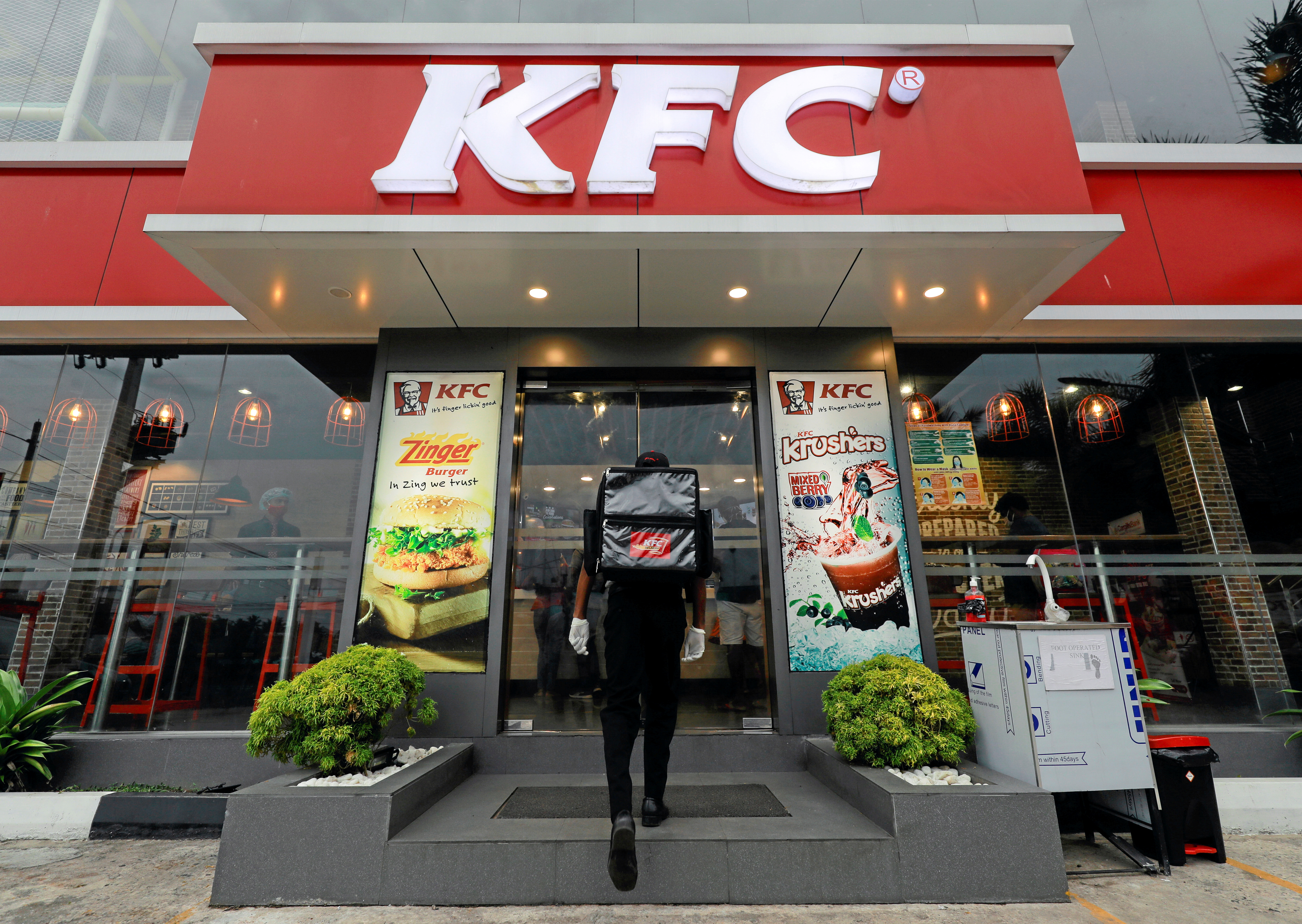 A delivery staff member wearing a protective mask enters a KFC fast food outlet after a delivery in Colombo