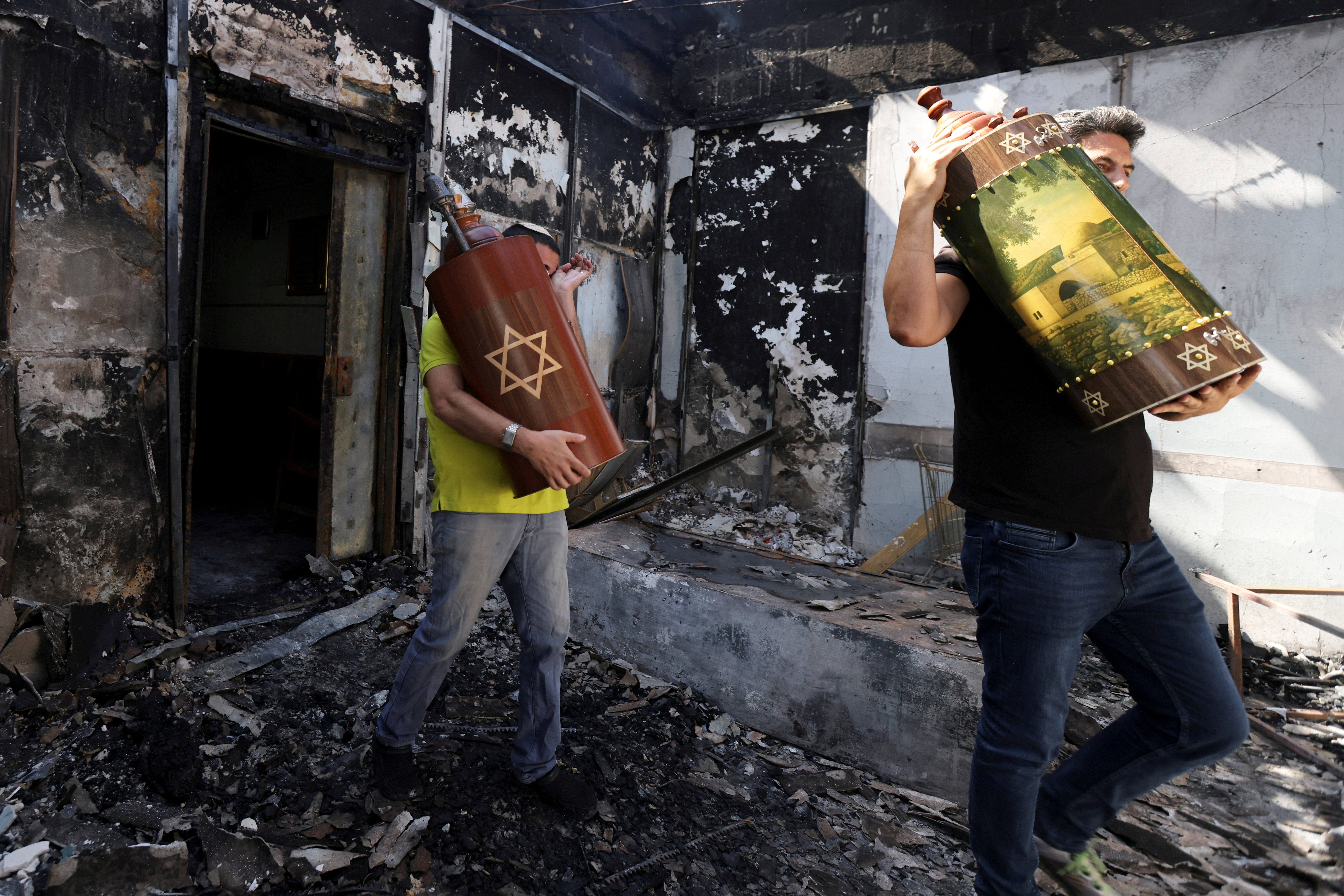 Torah scrolls, Jewish holy scriptures, are removed from a synagogue which was torched during violent confrontations in the city of Lod, Israel between Israeli Arab demonstrators and police, amid high tensions over hostilities between Israel and Gaza militants and tensions in Jerusalem May 12, 2021. REUTERS/Ronen Zvulun