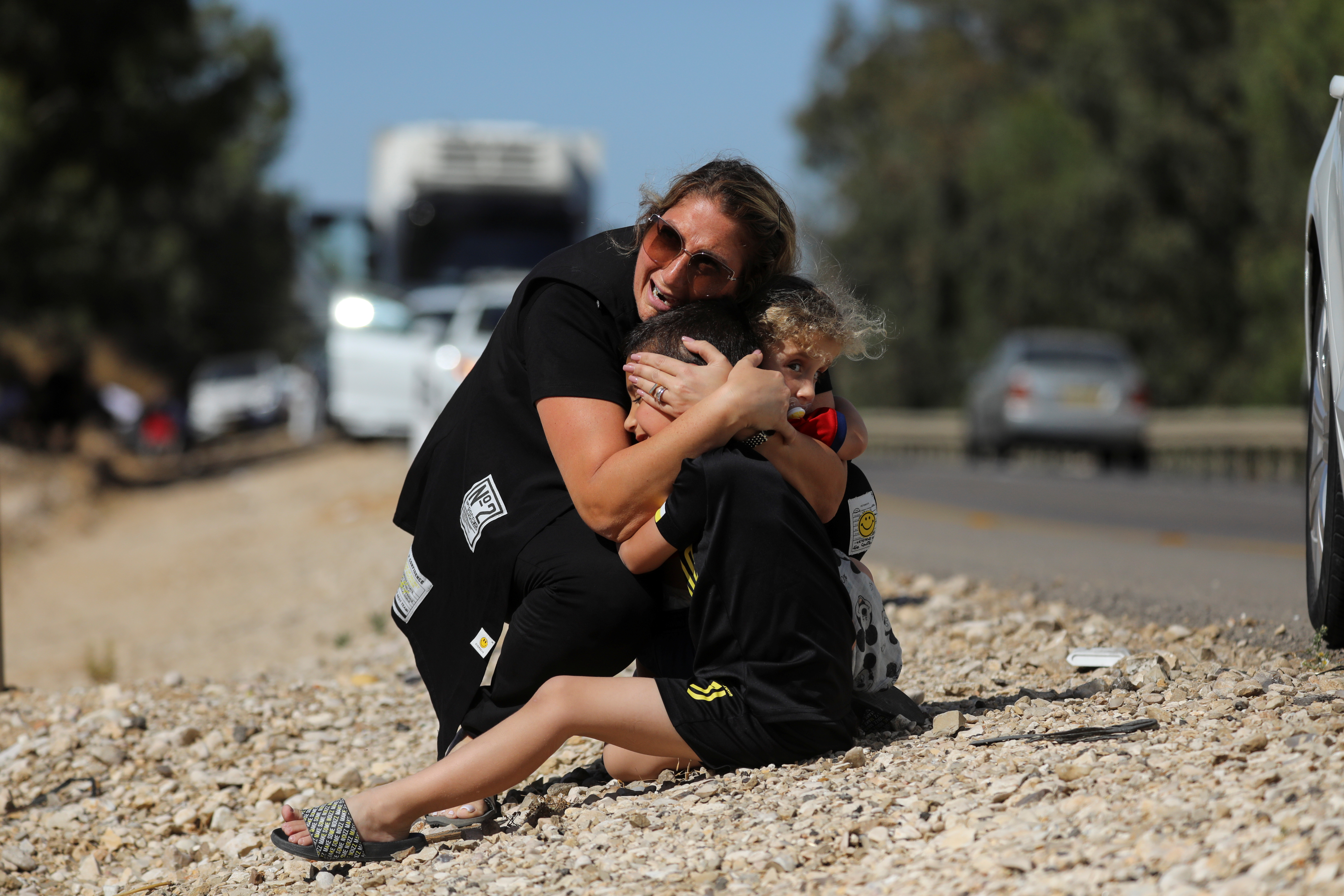 A woman protects her children as sirens sound following rocket launched from the Gaza Strip towards Israel near Sderot
