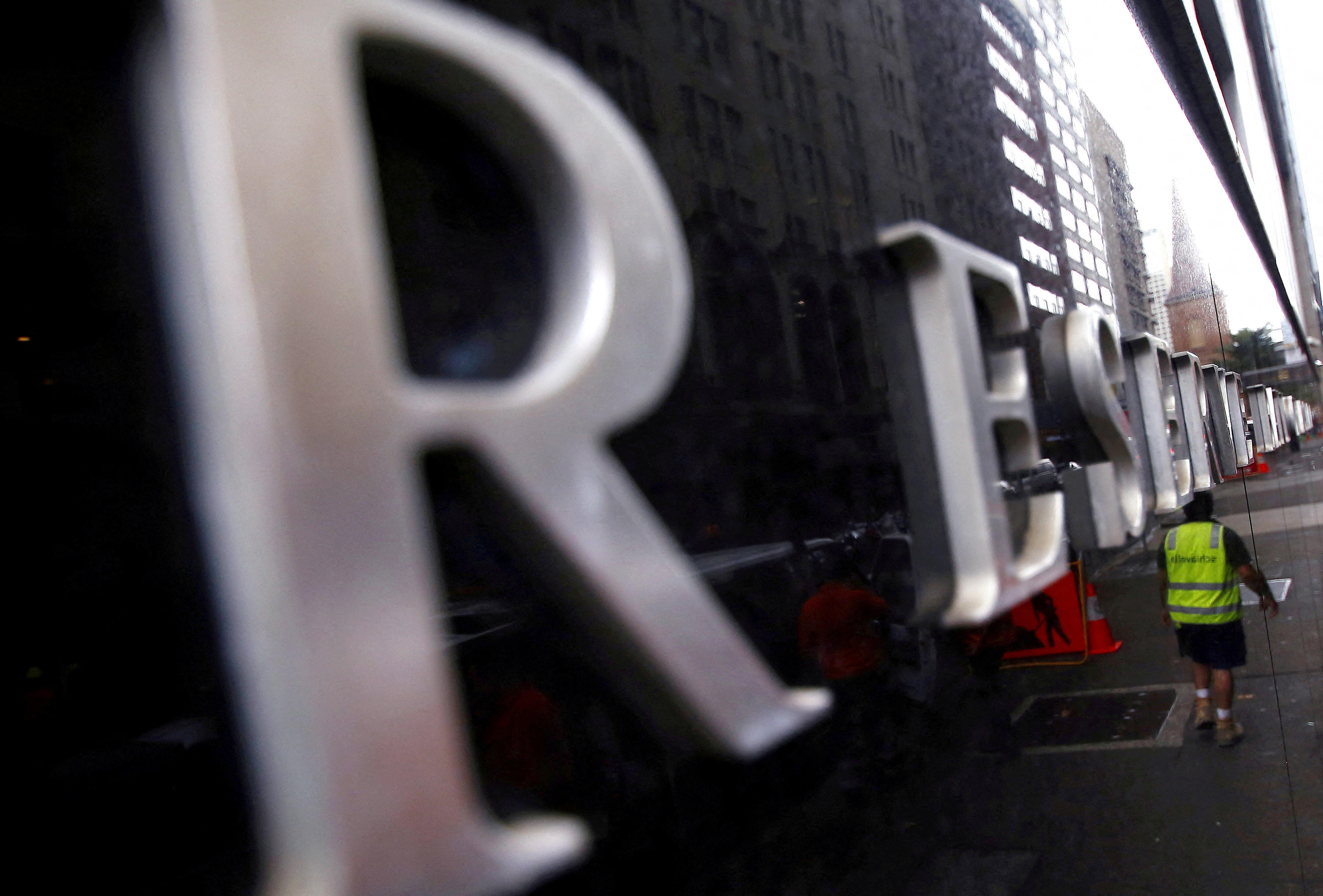 A worker is reflected in a wall of the Reserve Bank of Australia head office in central Sydney, Australia