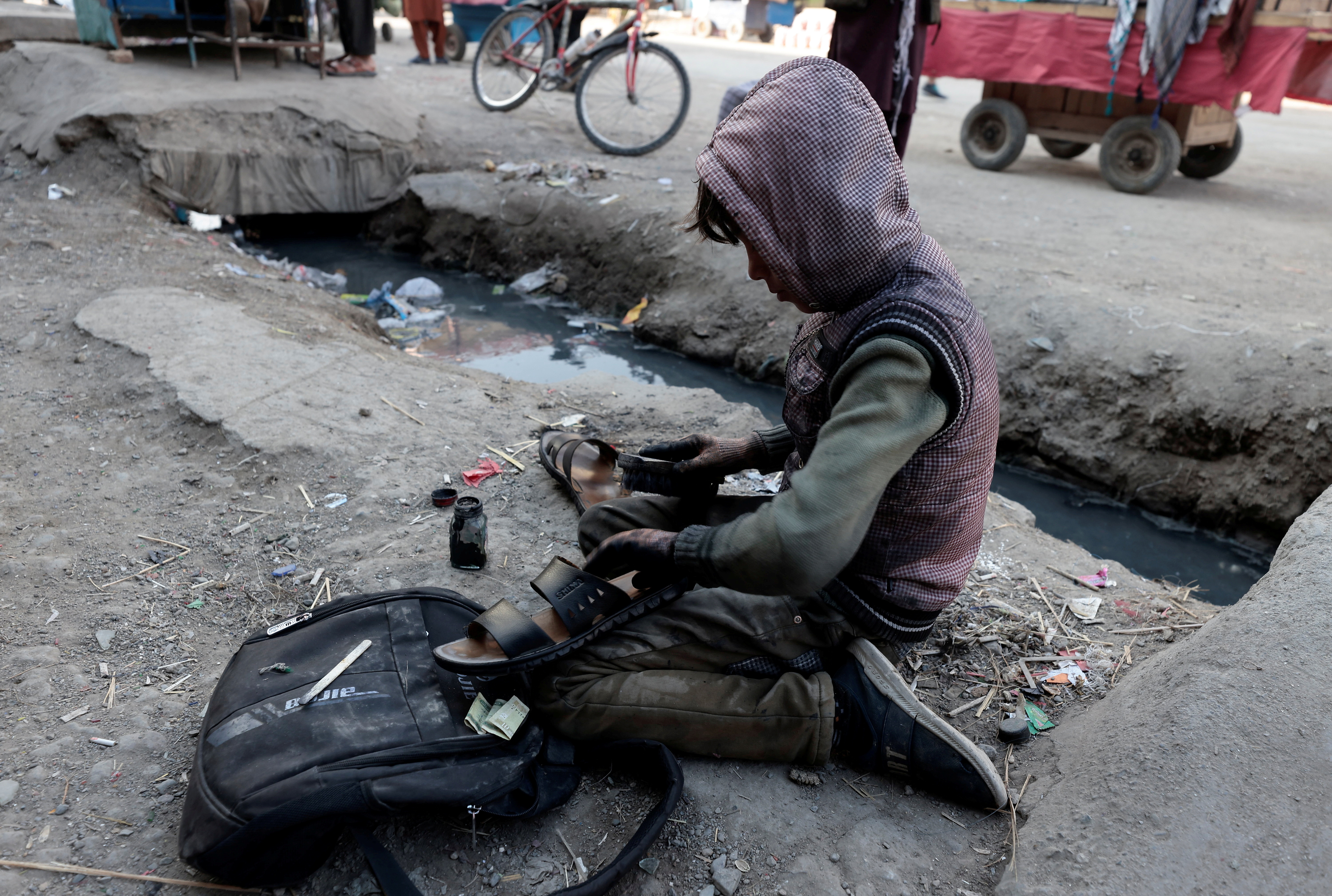 Самирулах, 11, момче што шие чевли чисти чевел покрај пазарот во Кабул, Авганистан, 29 октомври 2021 година. REUTERS/Zohra Bensemra