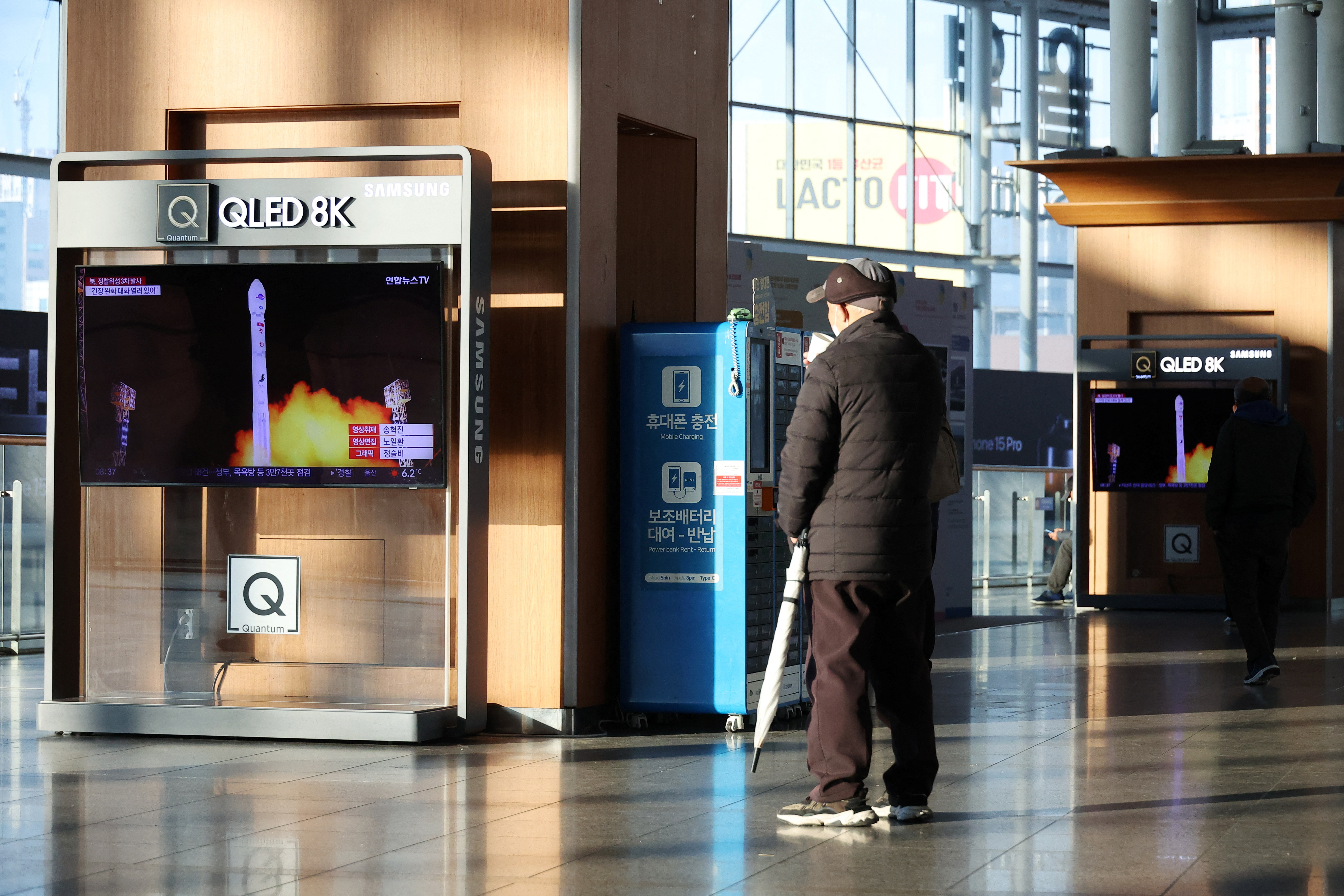 A man watches a TV broadcasting a news report on North Korea launching a military satellite, at a railway station in Seoul