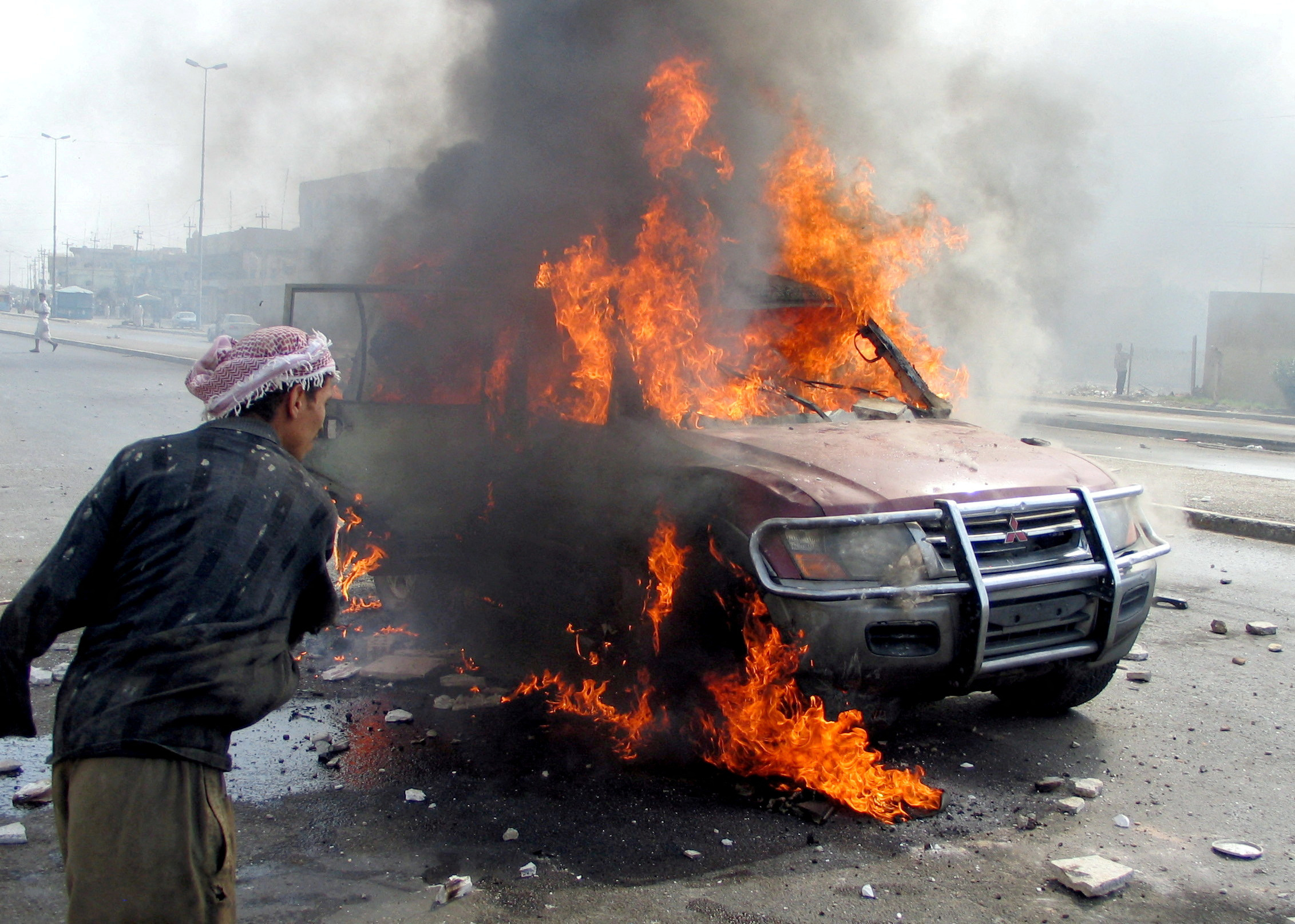 FILE PHOTO: Iraqi man looks at blazing vehicle after attack in Falluja