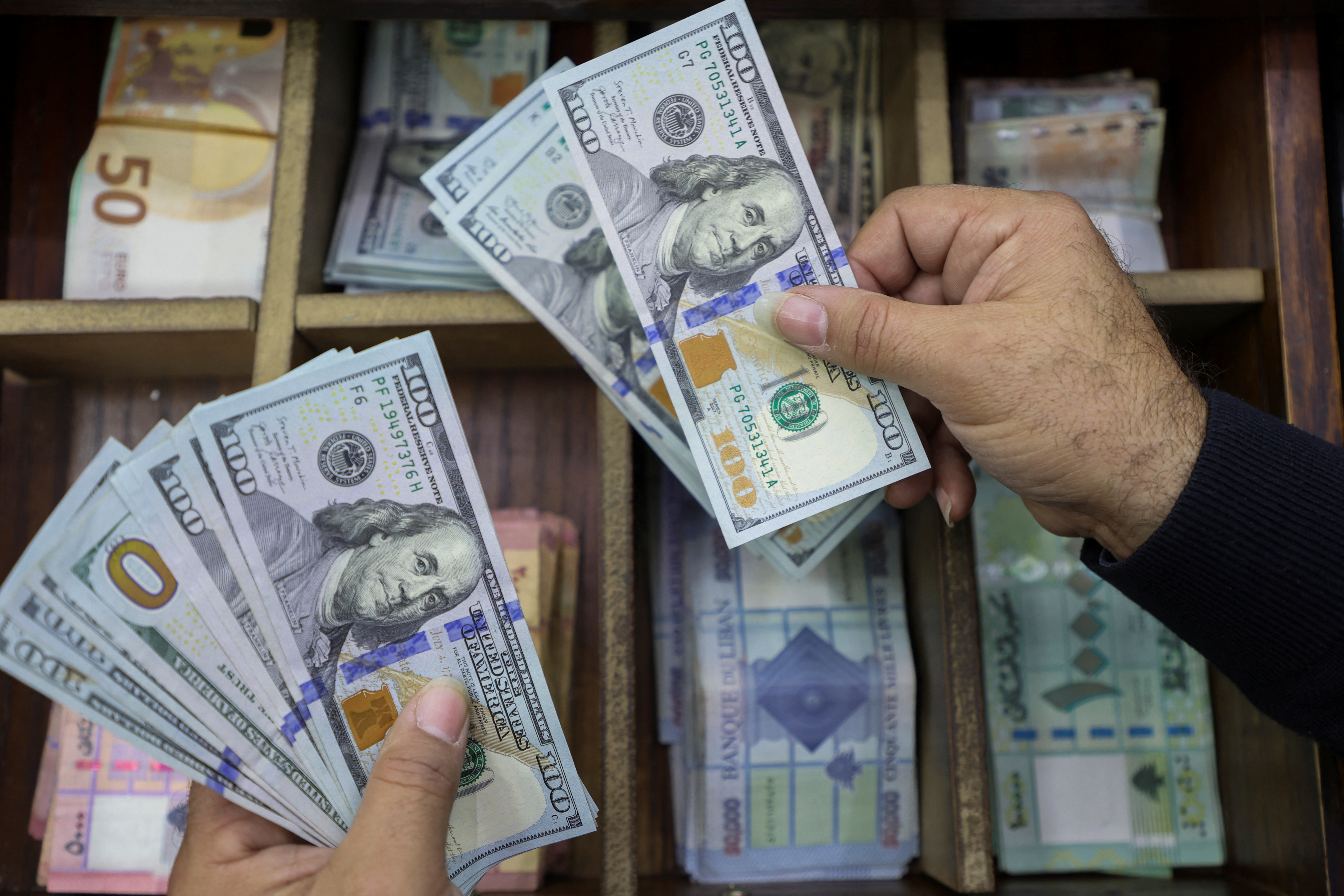 A money exchange vendor holds U.S. dollar banknotes at his shop in Beirut