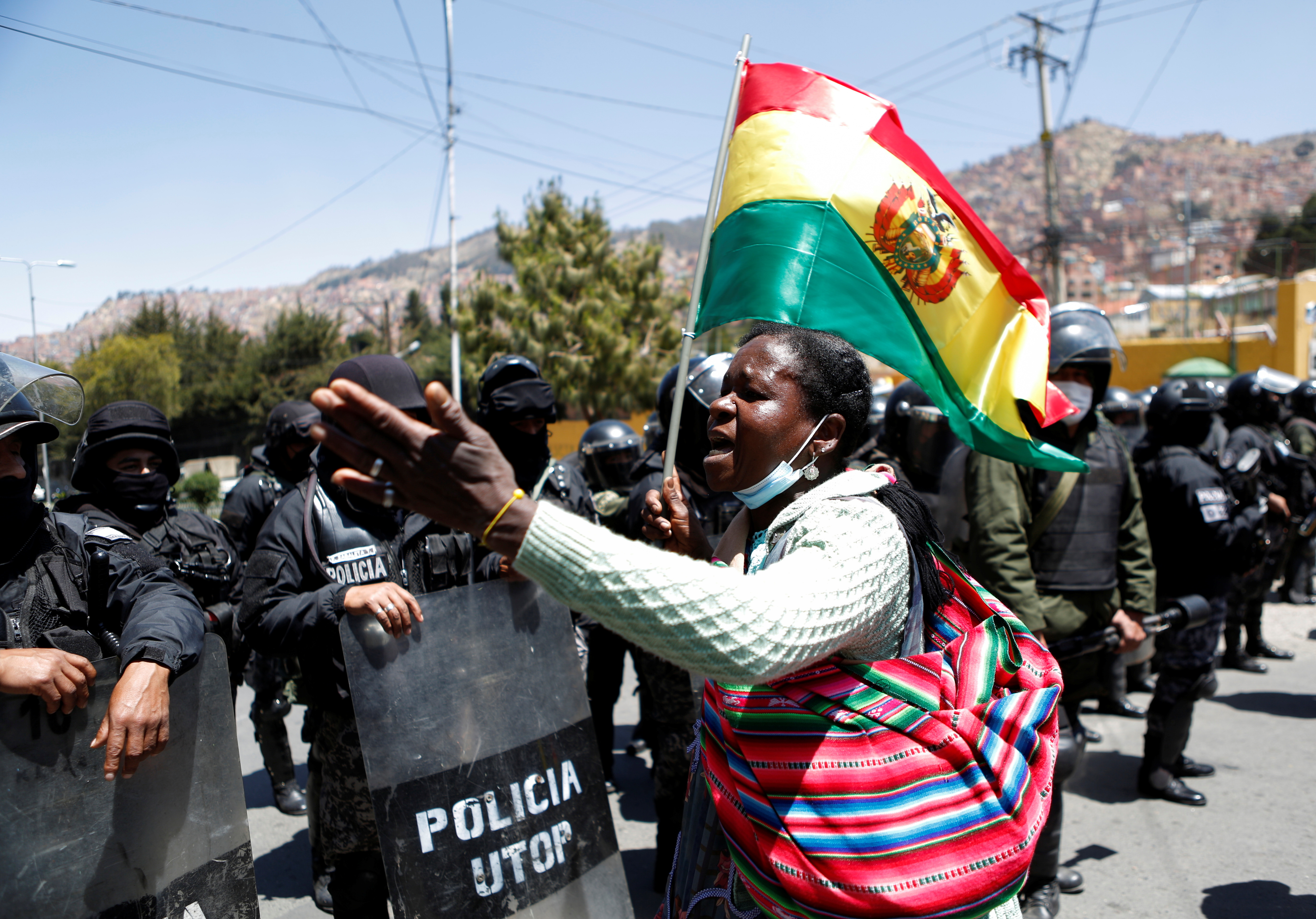 A coca grower from the Yungas region gestures in front of police during a protest over the control of the leaf's main market, in La Paz, Bolivia, September 28, 2021. REUTERS/Manuel Claure