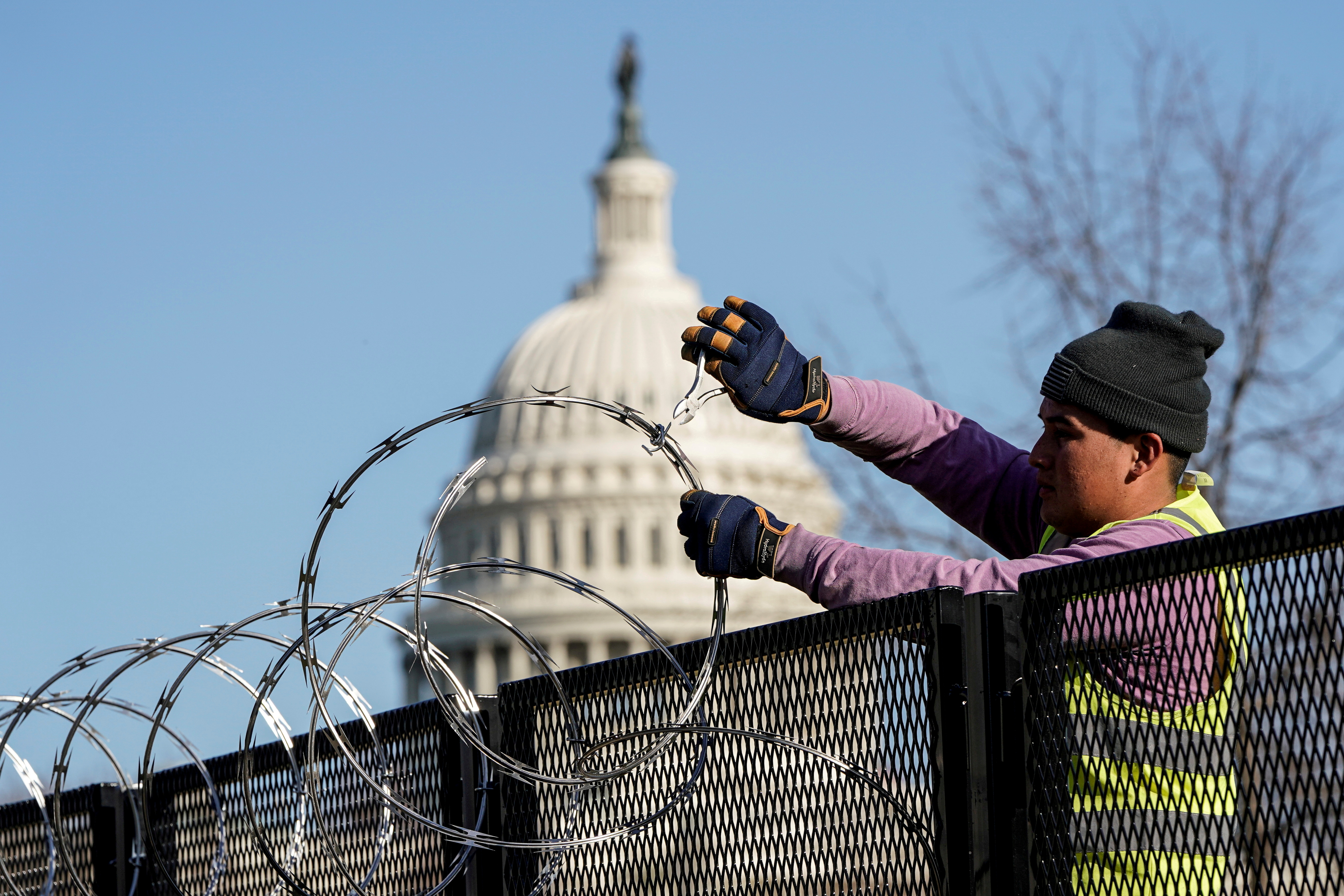 Workers remove razor wire from security fencing near the U.S. Capitol in Washington