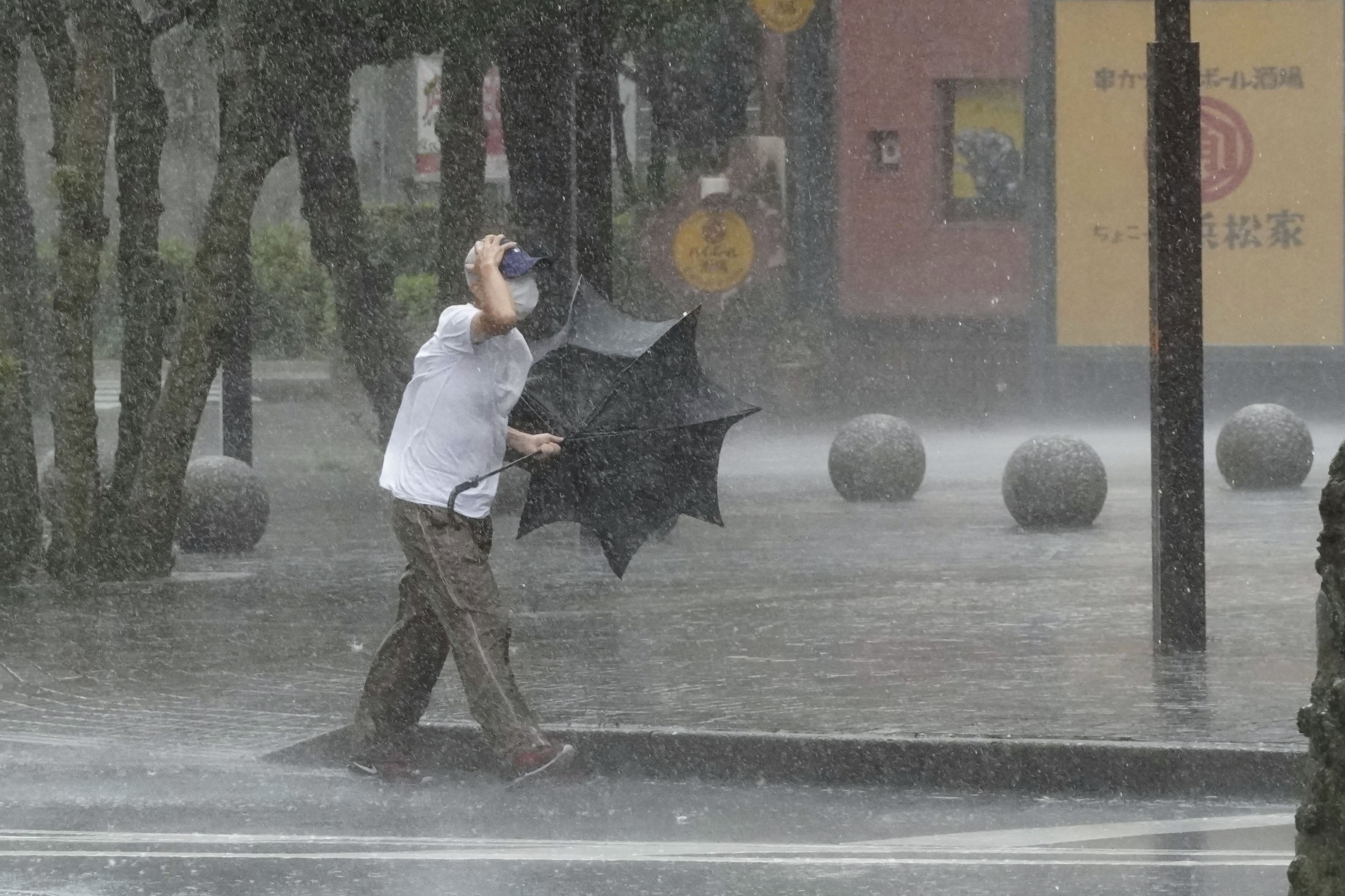 A man walks on the street in the heavy rain caused by Tropical Storm Meari in Hamamatsu, Japan