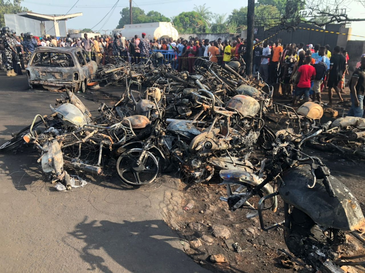 People watch burnt car and motorcycles after a fuel tanker explosion in Freetown