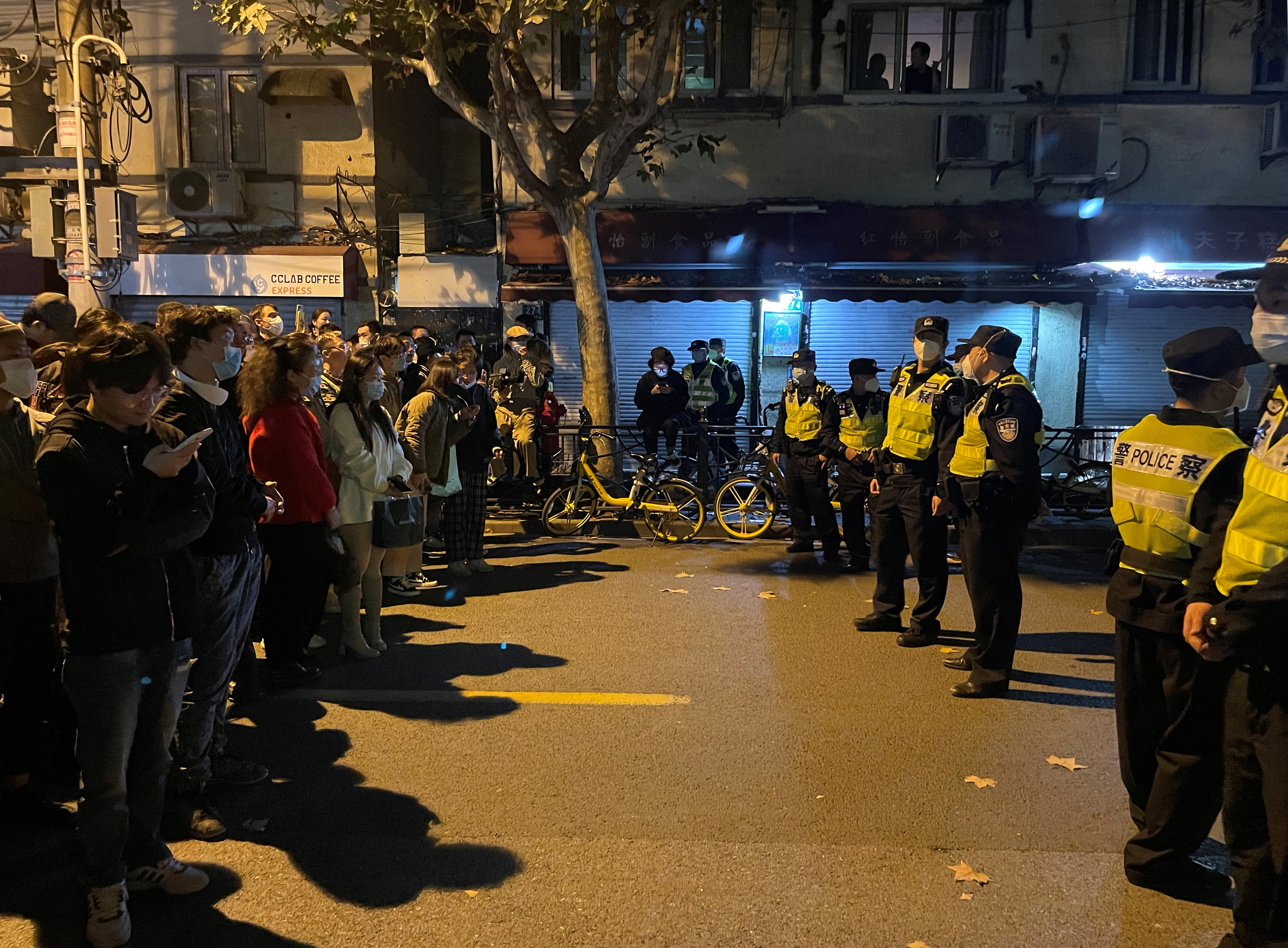 People stand in front of a line of police officers in Shanghai