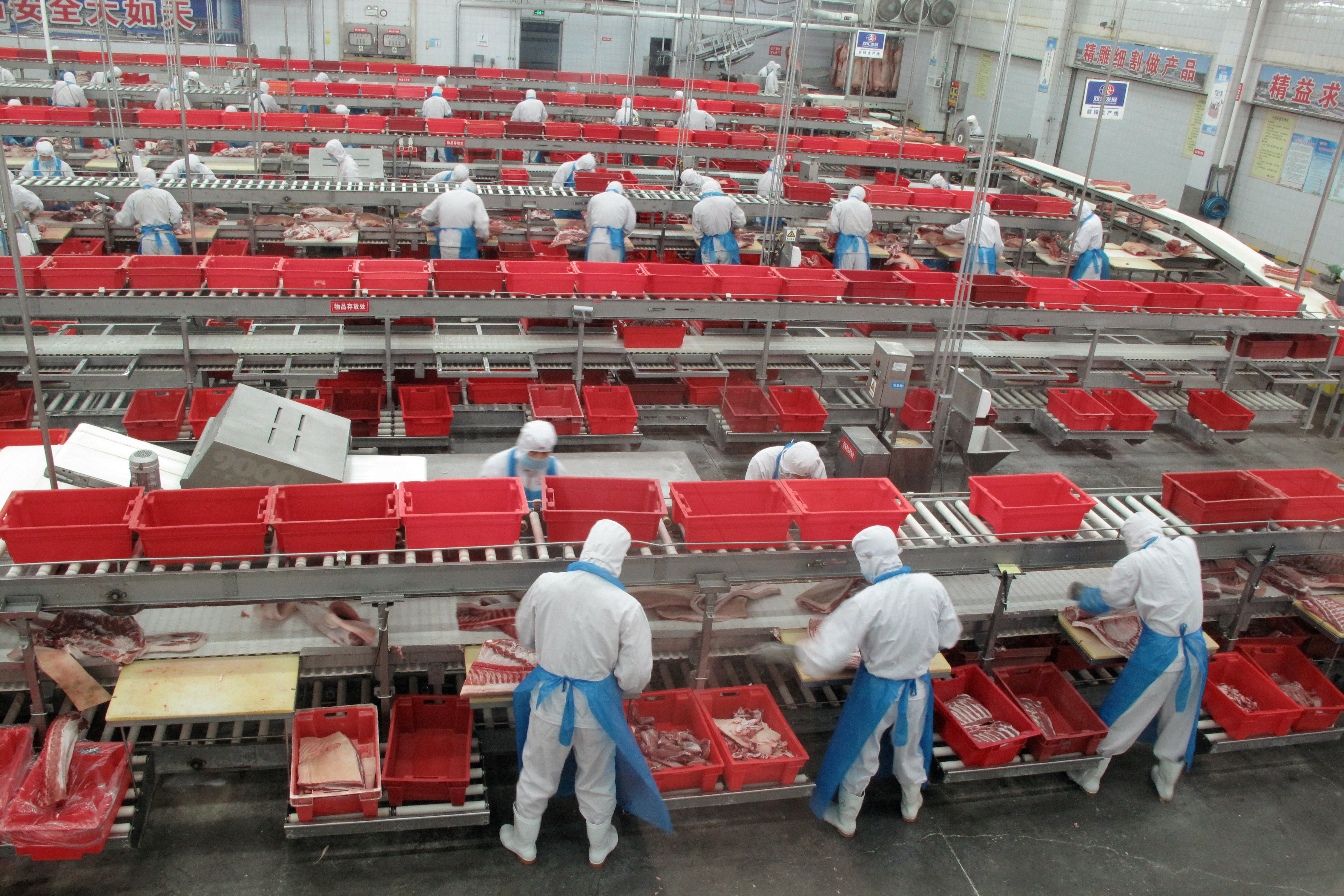 Workers sort cuts of fresh pork in a processing plant of pork producer WH Group in Zhengzhou