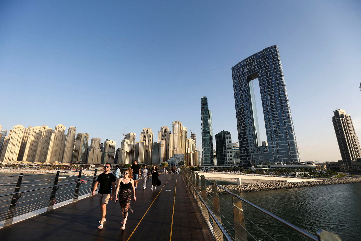 People walk on the Pedestrian Bridge at the Bluewaters Island in Dubai