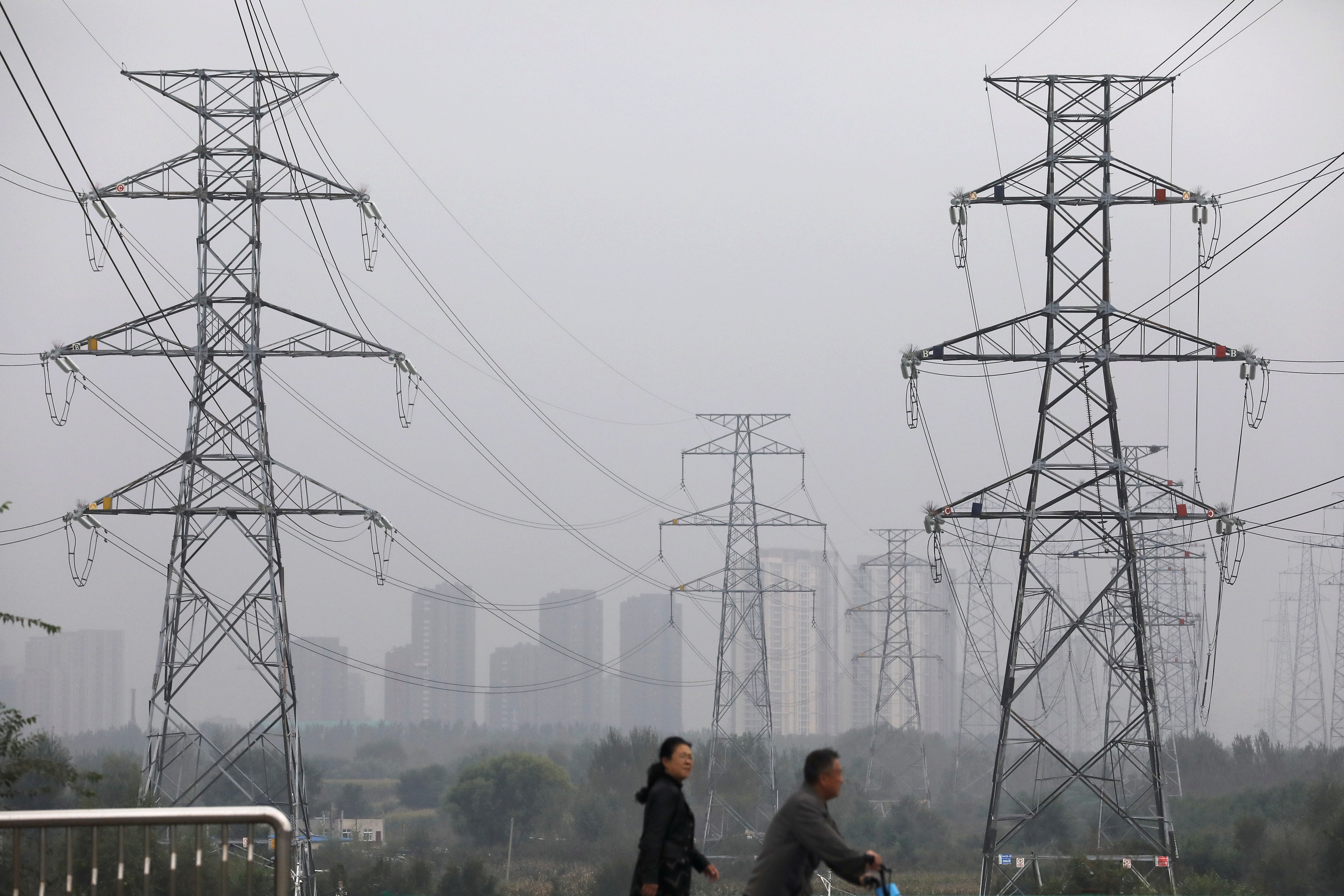People walk past electricity pylons in Shenyang