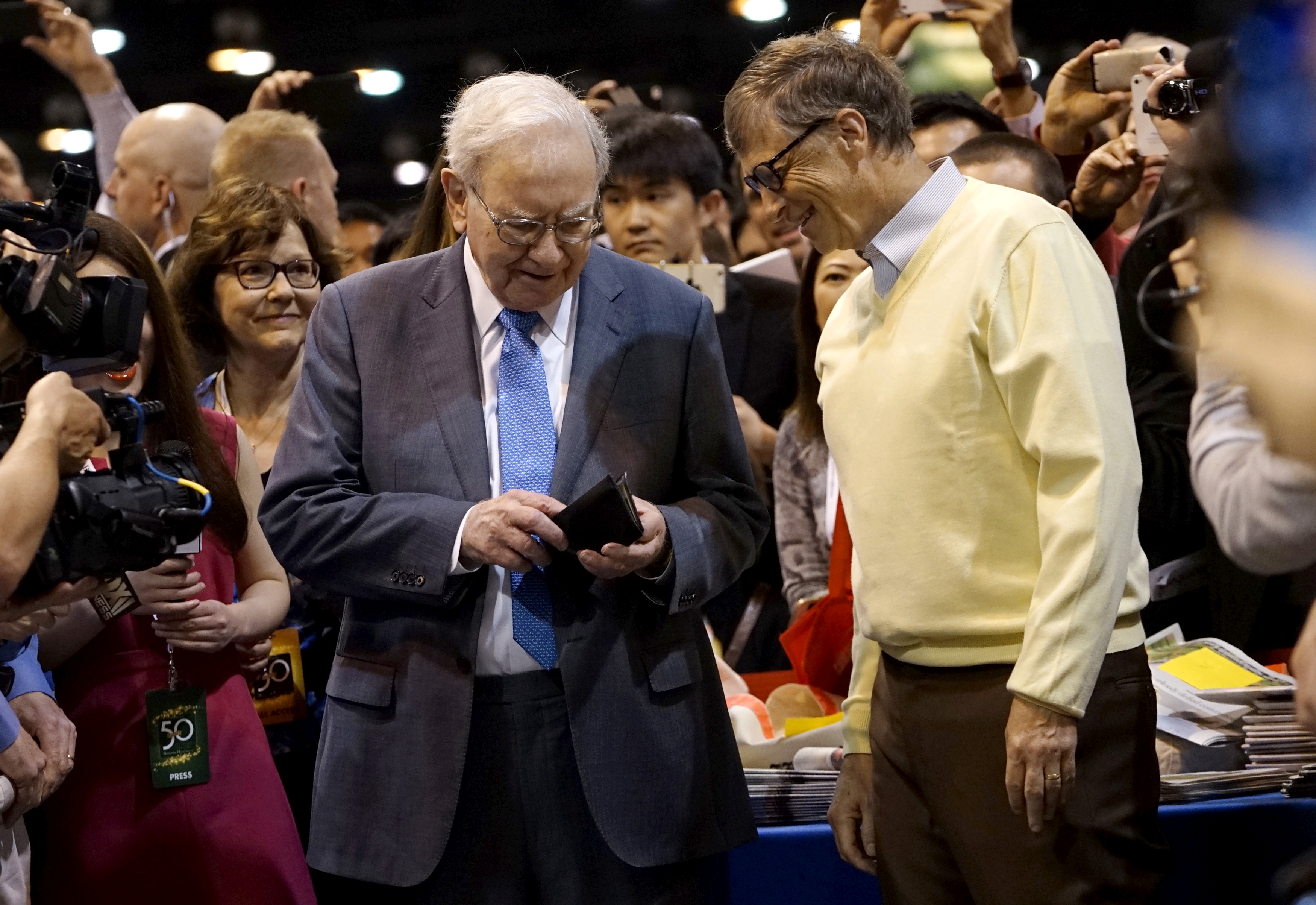 Berkshire Hathaway CEO Warren Buffett gets his wallet out to pay a bet to Microsoft co-founder Bill Gates after participating in a newspaper throwing contest prior to the Berkshire annual meeting in Omaha